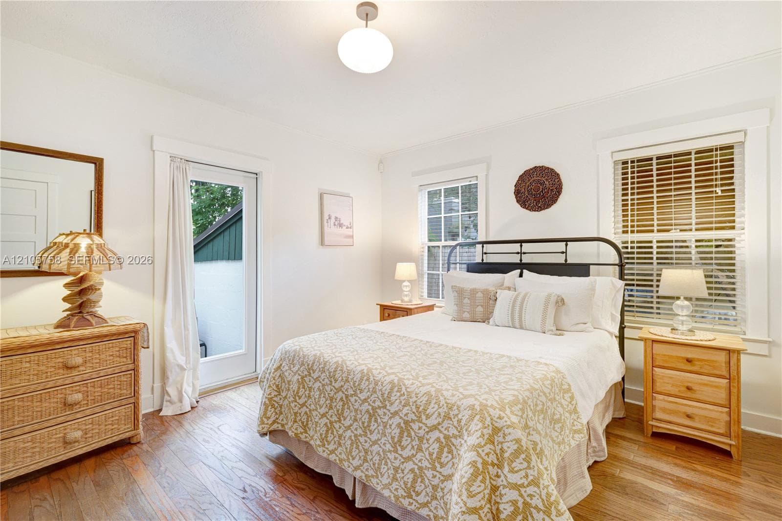 Wood-finish flooring, glass-paned door, multi-pane windows with horizontal blinds, and globe-style ceiling fixture