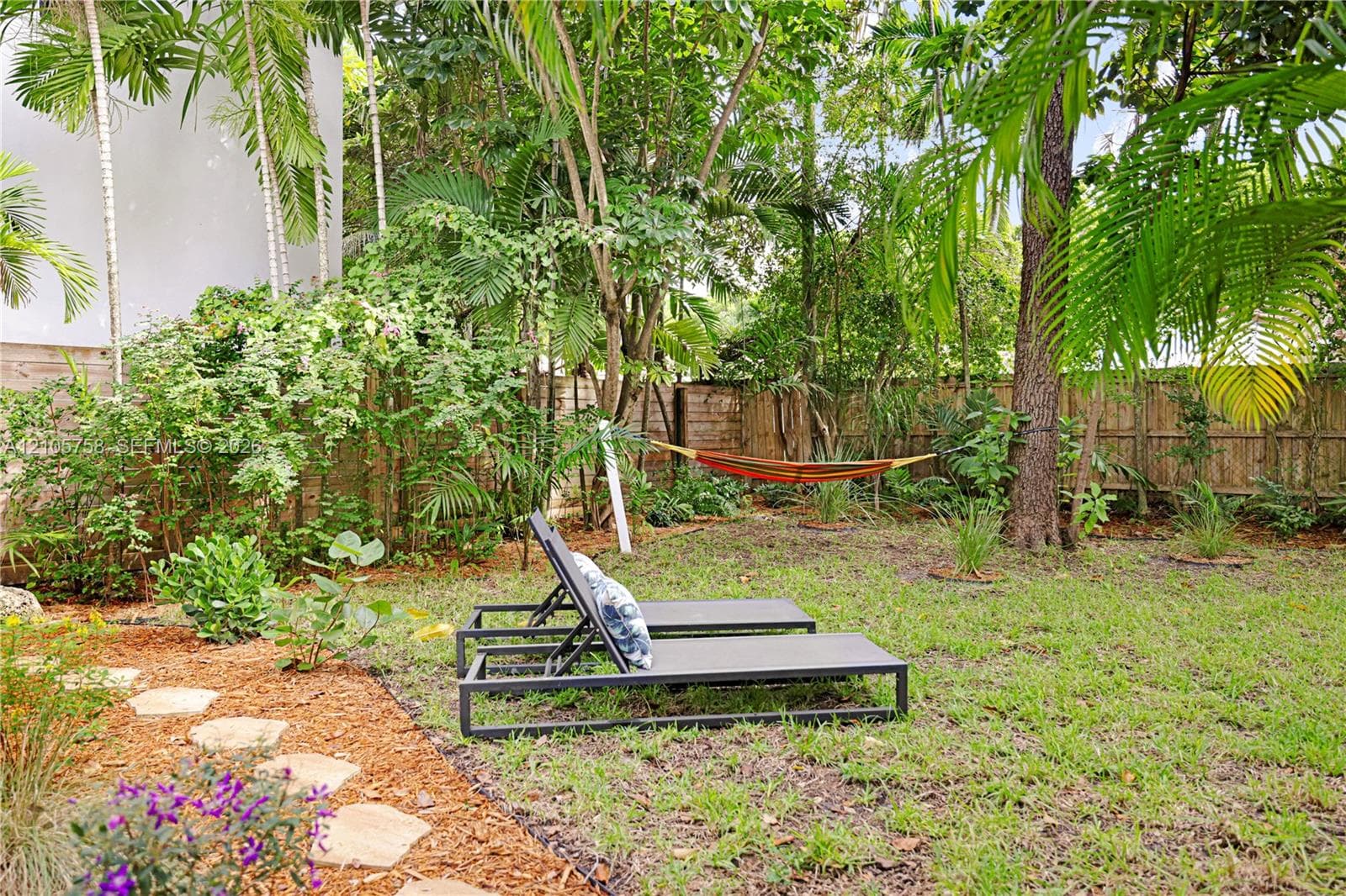 Private backyard featuring mature landscaping, natural stone pavers, and perimeter wood fencing
