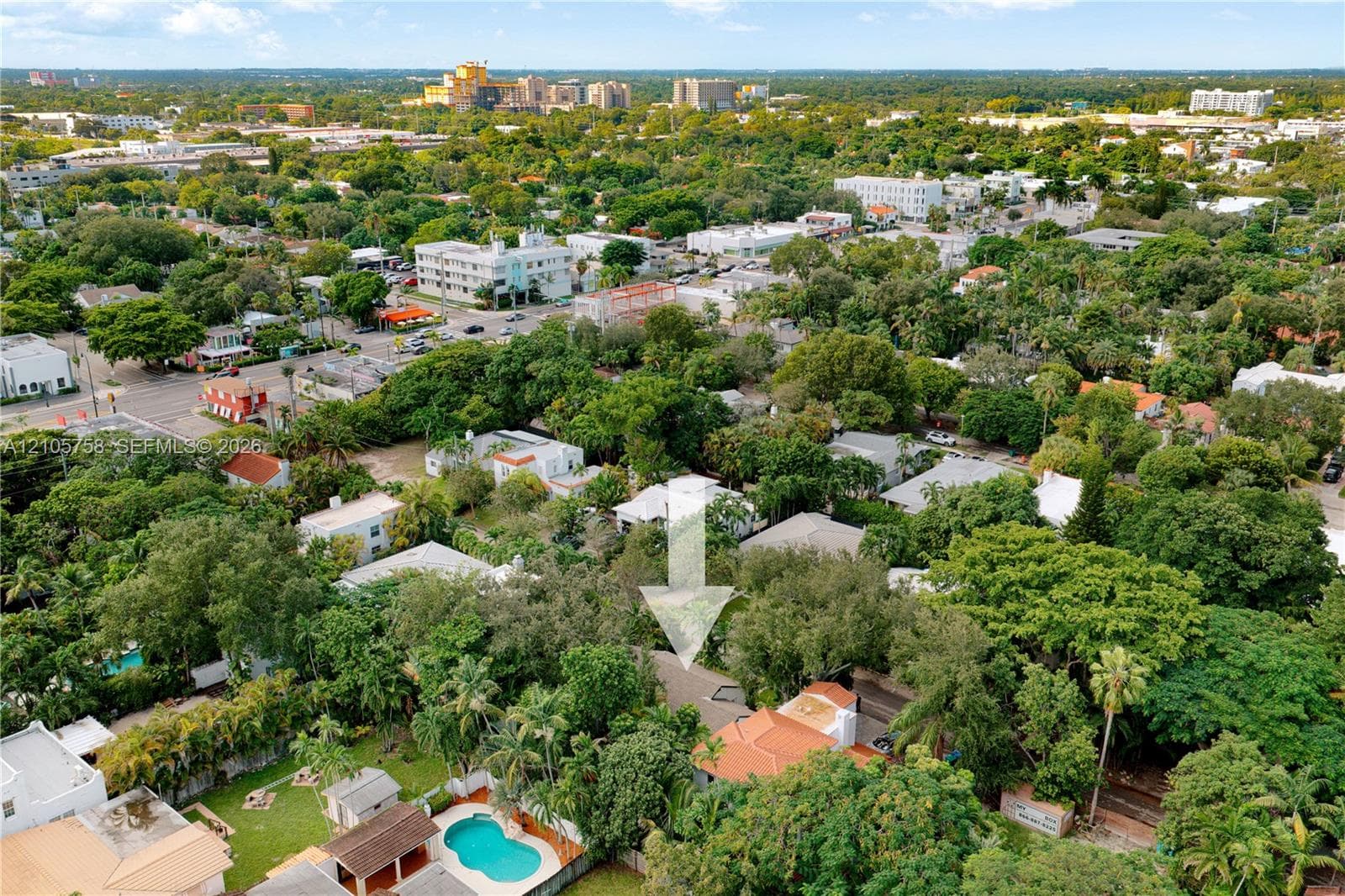 Aerial perspective of property featuring mature trees, a swimming pool, and a tile roof