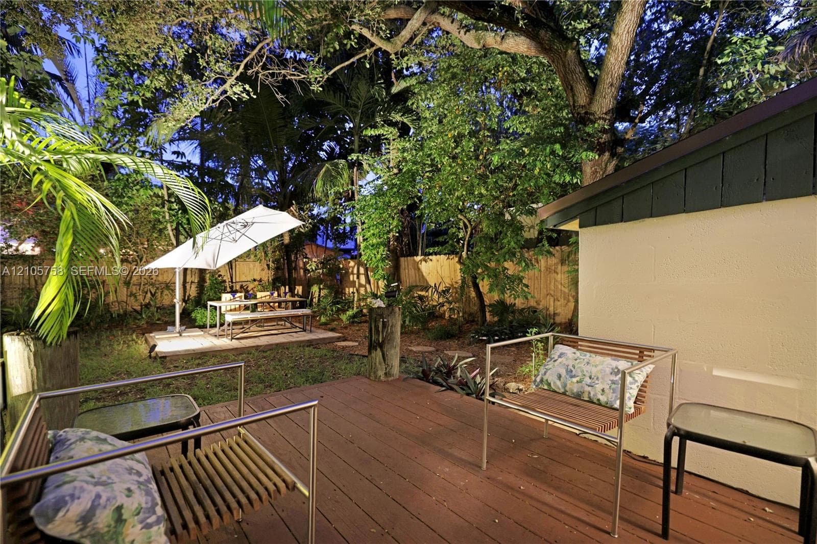 Outdoor deck featuring wood-finish decking and perimeter fencing, surrounded by mature trees and landscaped grounds