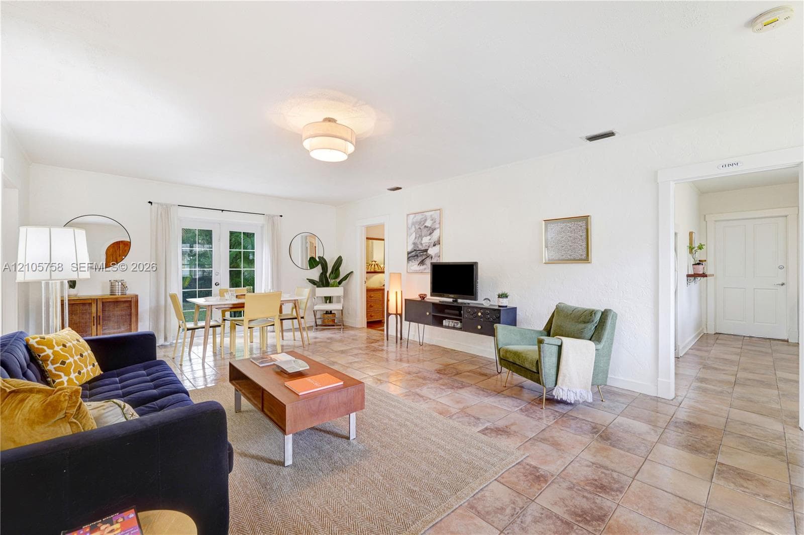 Living area featuring square tile flooring, semi-flush mount ceiling lighting, and glass-paneled double doors