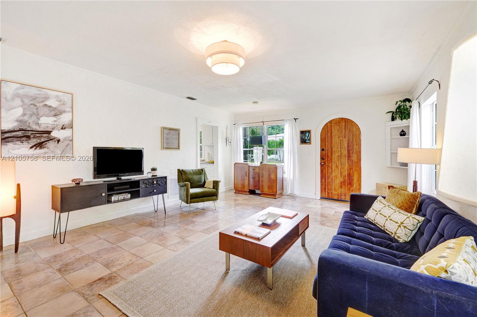Living area featuring natural stone tile flooring, an arched wood entry door, and built-in shelving