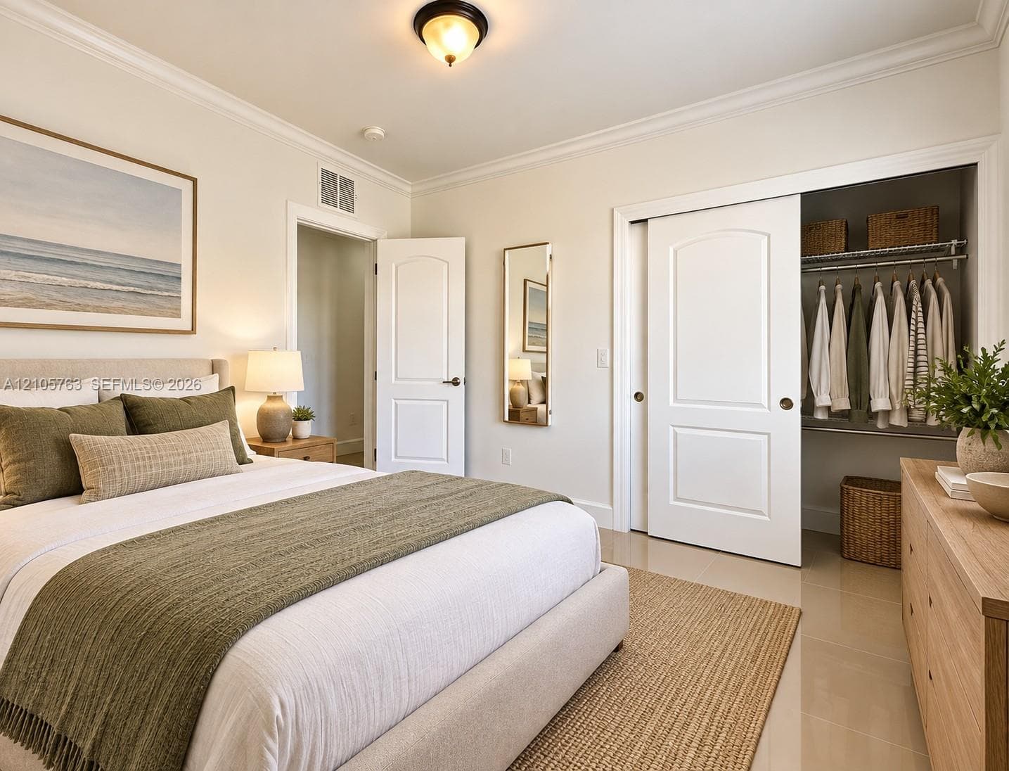 Neutral-toned room featuring crown molding, polished tile flooring, a walk-in closet with sliding doors, and a flush-mount ceiling fixture