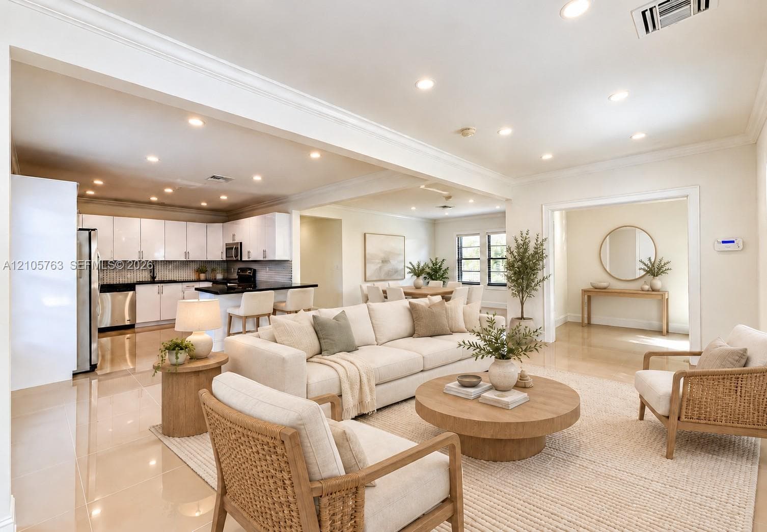 Open-concept interior featuring recessed lighting, polished tile flooring, crown molding, and a kitchen equipped with white cabinetry and dark countertops