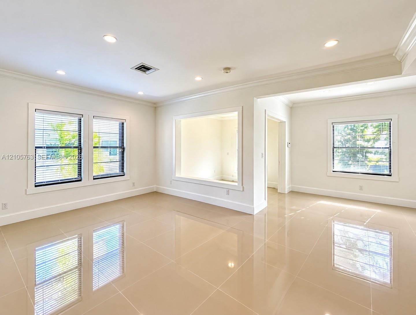 Neutral-toned tile flooring, recessed ceiling lighting, crown molding, double-hung windows, and a recessed wall niche
