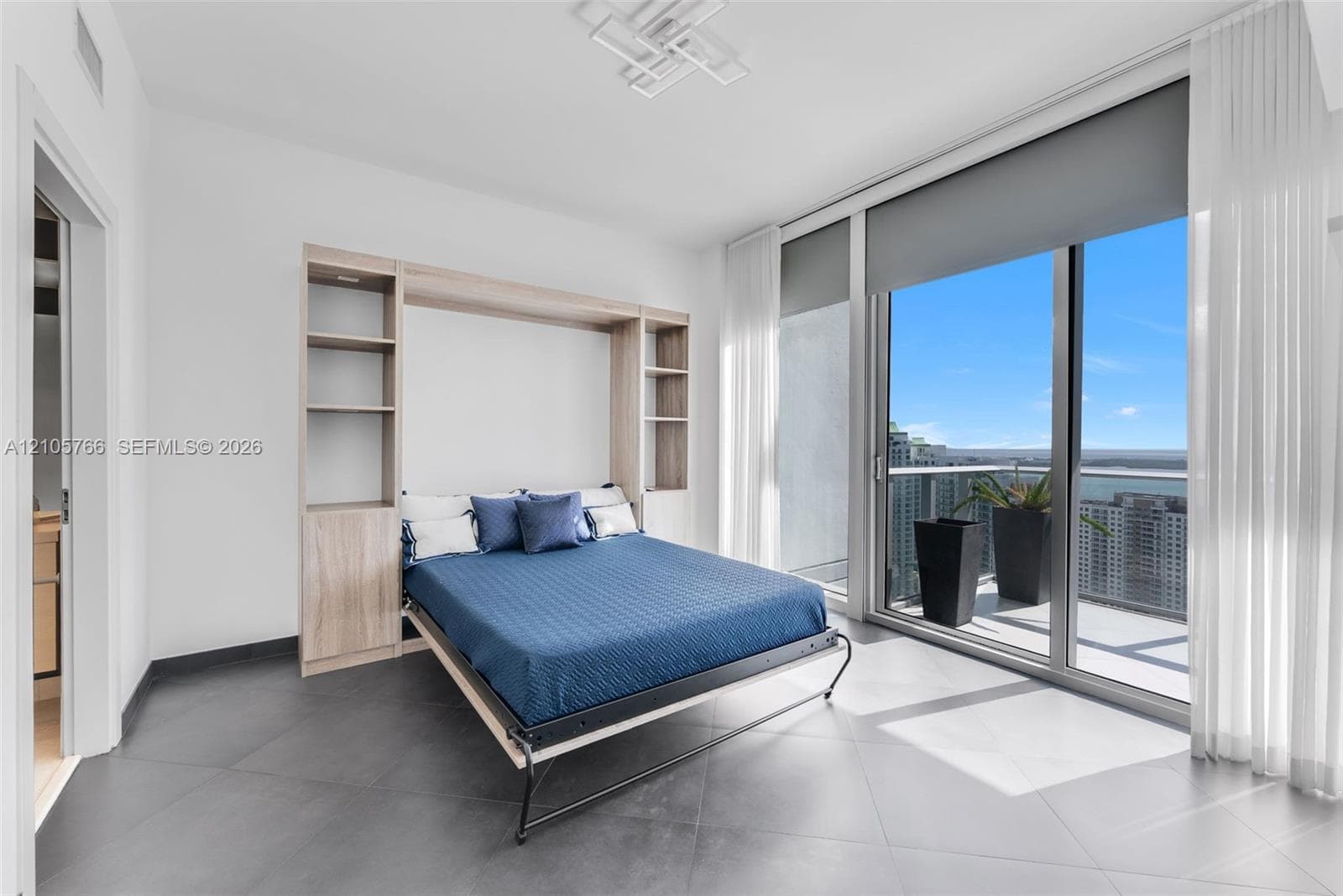 Secondary bedroom with Murphy bed, built-in shelving and sliding doors to the terrace.