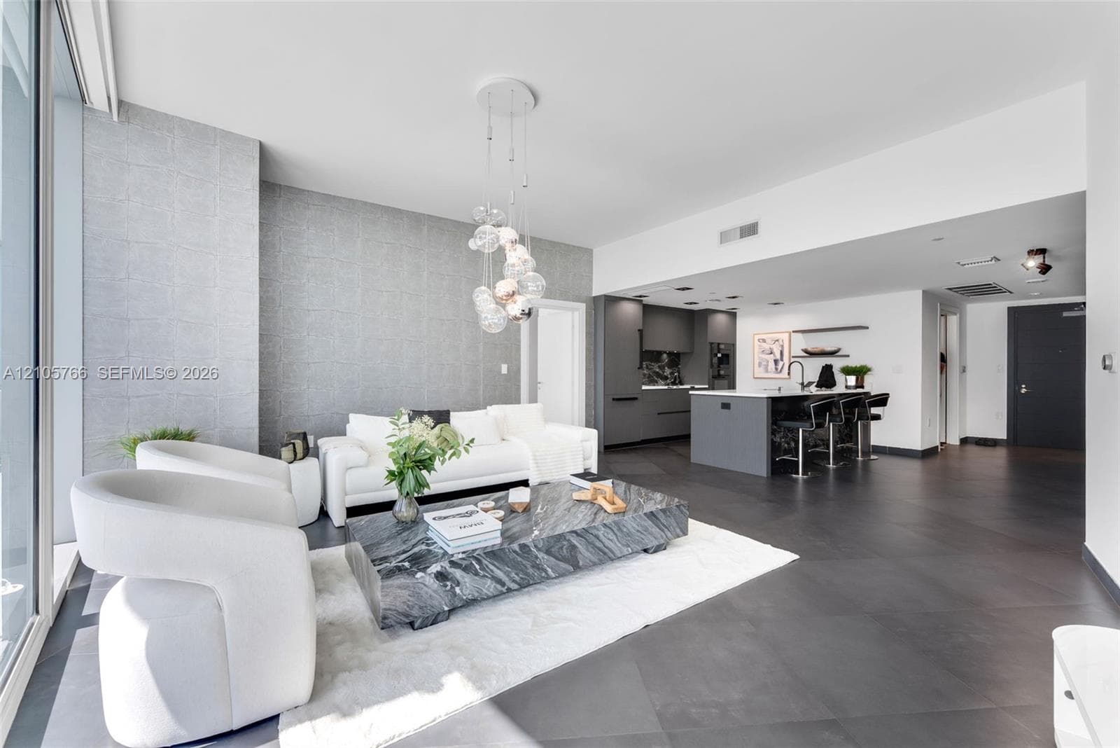Living room with floor-to-ceiling glass, open to the kitchen island with seating for 3.