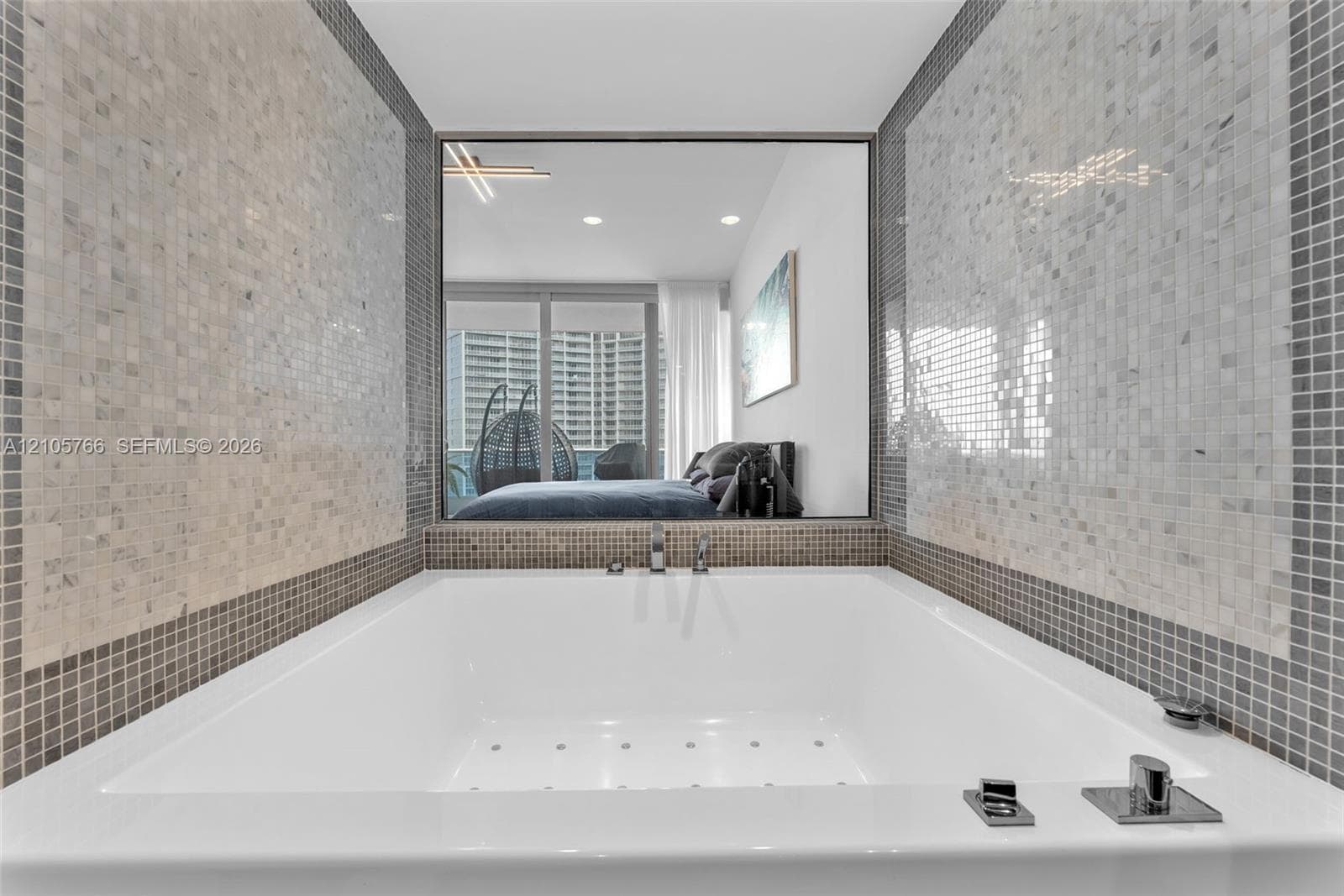 Jetted tub in the primary bath, with an interior glass window into the primary bedroom.