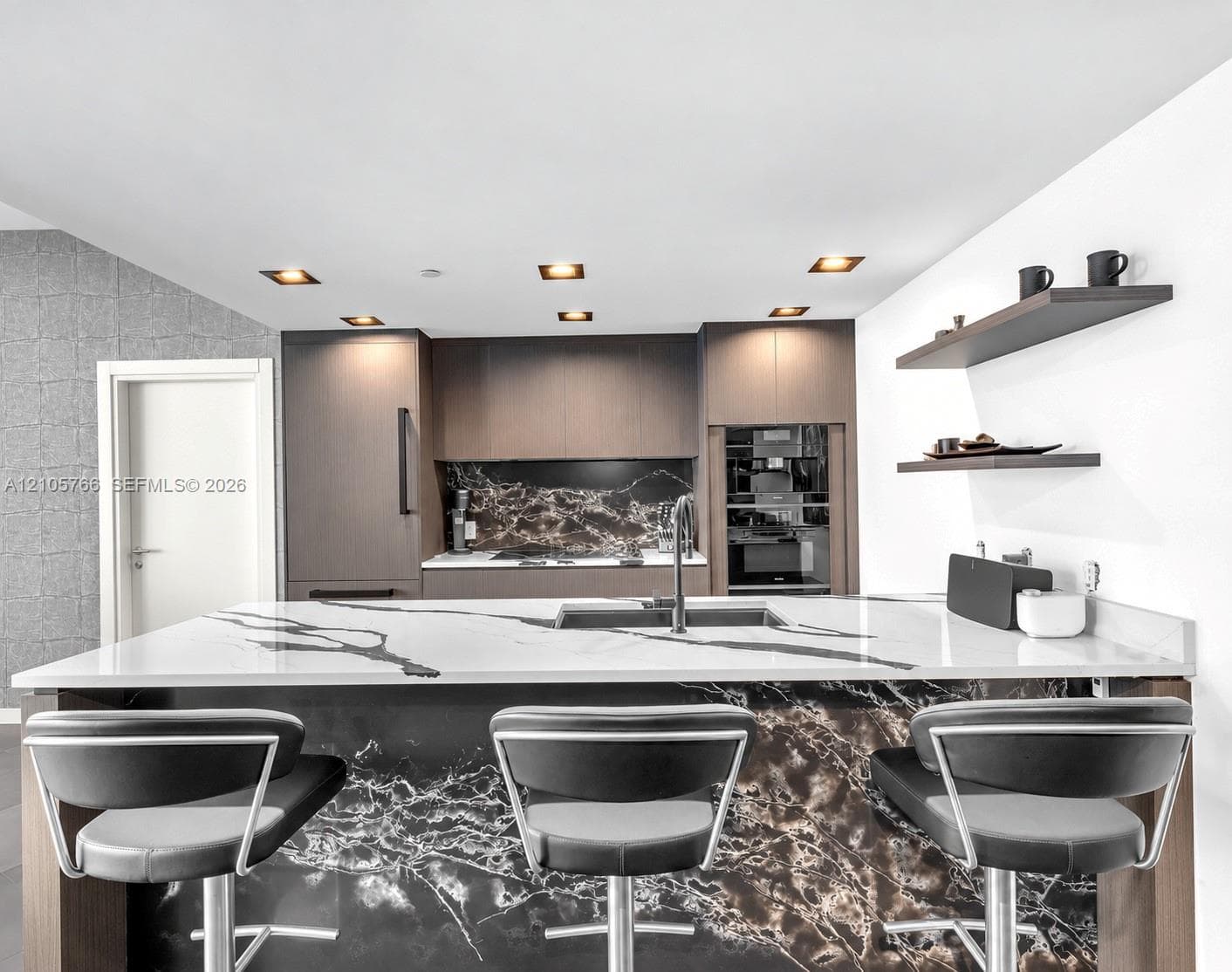 Kitchen island with sink and seating for 3, facing the Miele oven and coffee column.