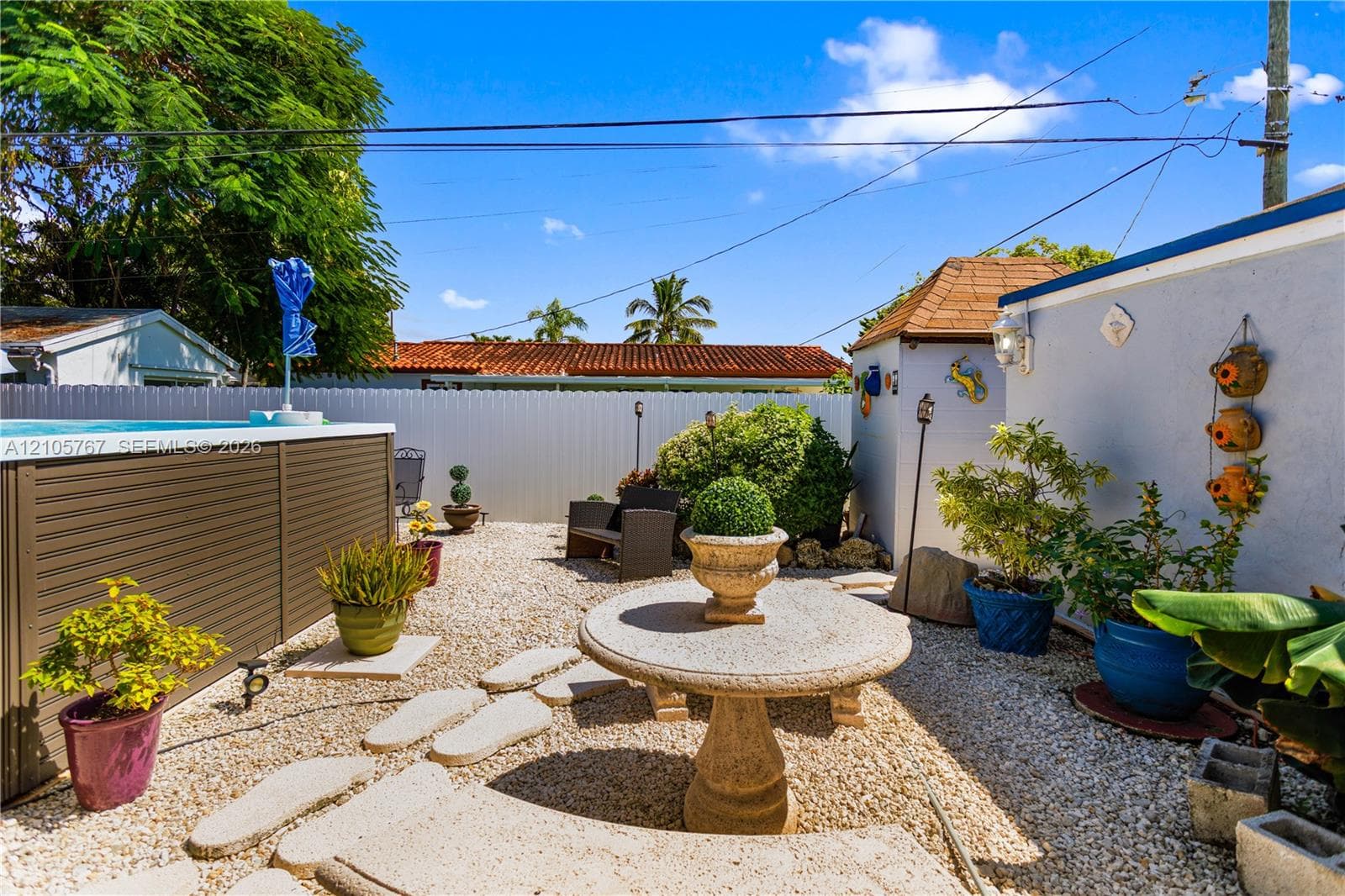 Low-maintenance gravel courtyard featuring an elevated pool, stone-finish pedestal table, and privacy fencing