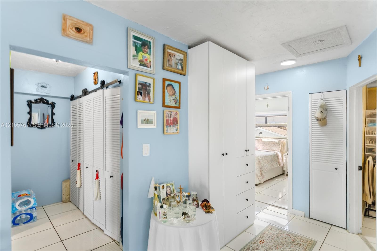 Interior space featuring light-toned tile flooring, floor-to-ceiling white built-in cabinetry, and multiple white louvered-style closet doors