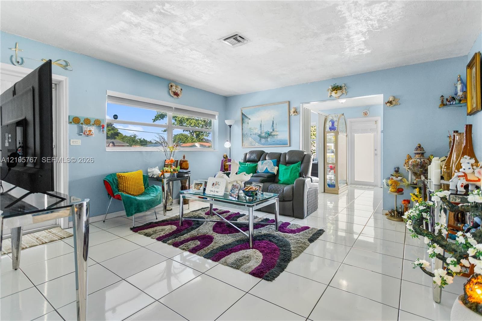 Living area featuring large-format ceramic tile flooring, expansive horizontal sliding windows, and a glass-paneled interior entry door