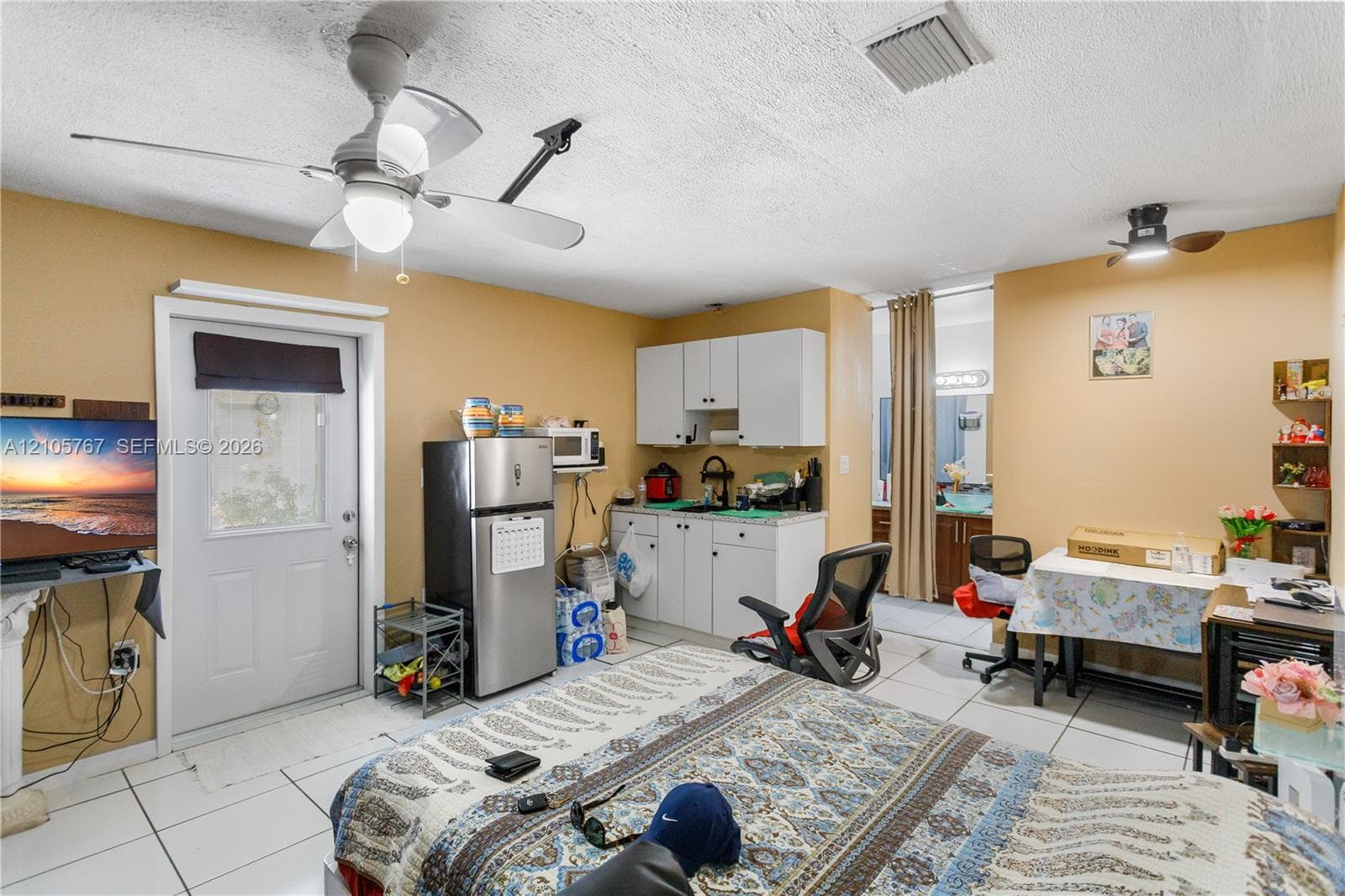White cabinetry, integrated sink, tile flooring, dual ceiling fans, and an exterior door with an inset window