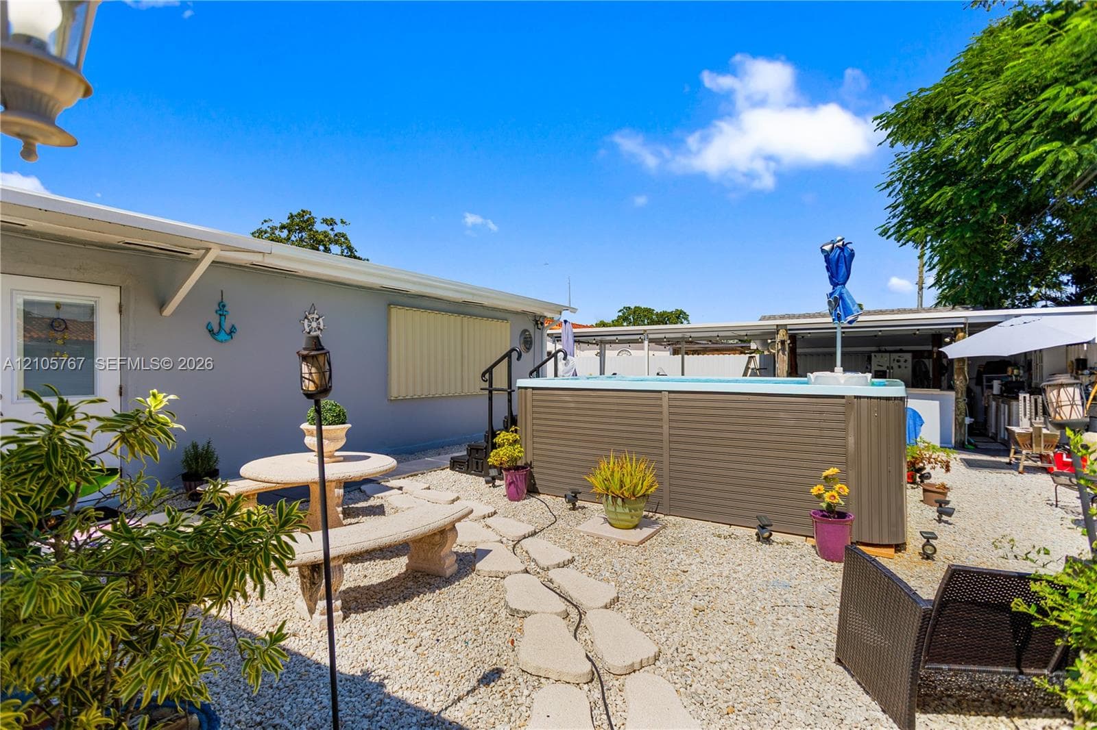 Outdoor space featuring a gravel ground surface, stone-style seating area, built-in above-ground pool, and covered patio structure