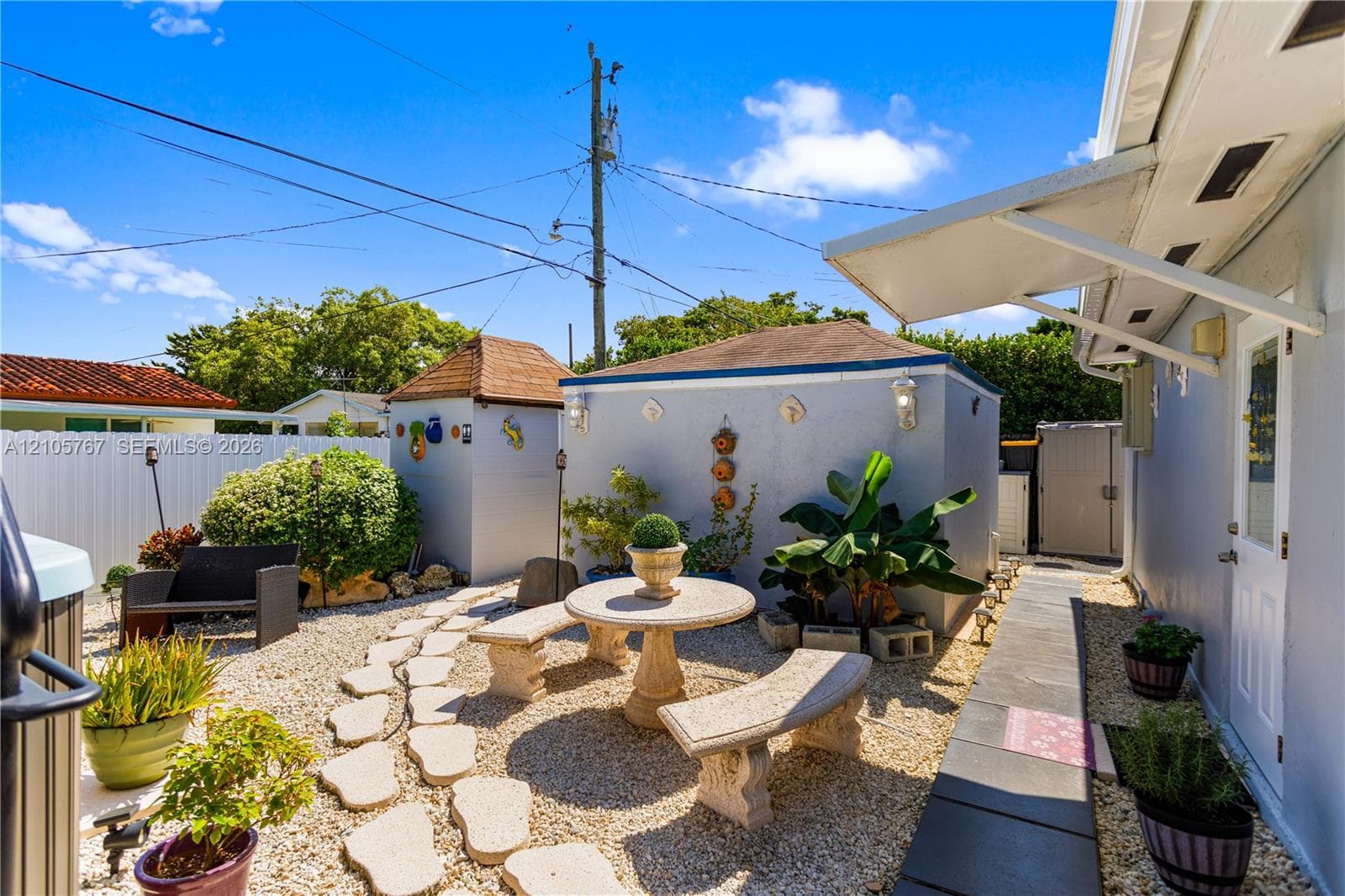 Low-maintenance stone-aggregate courtyard featuring an integrated stone patio set, a detached storage structure, and a paved walkway