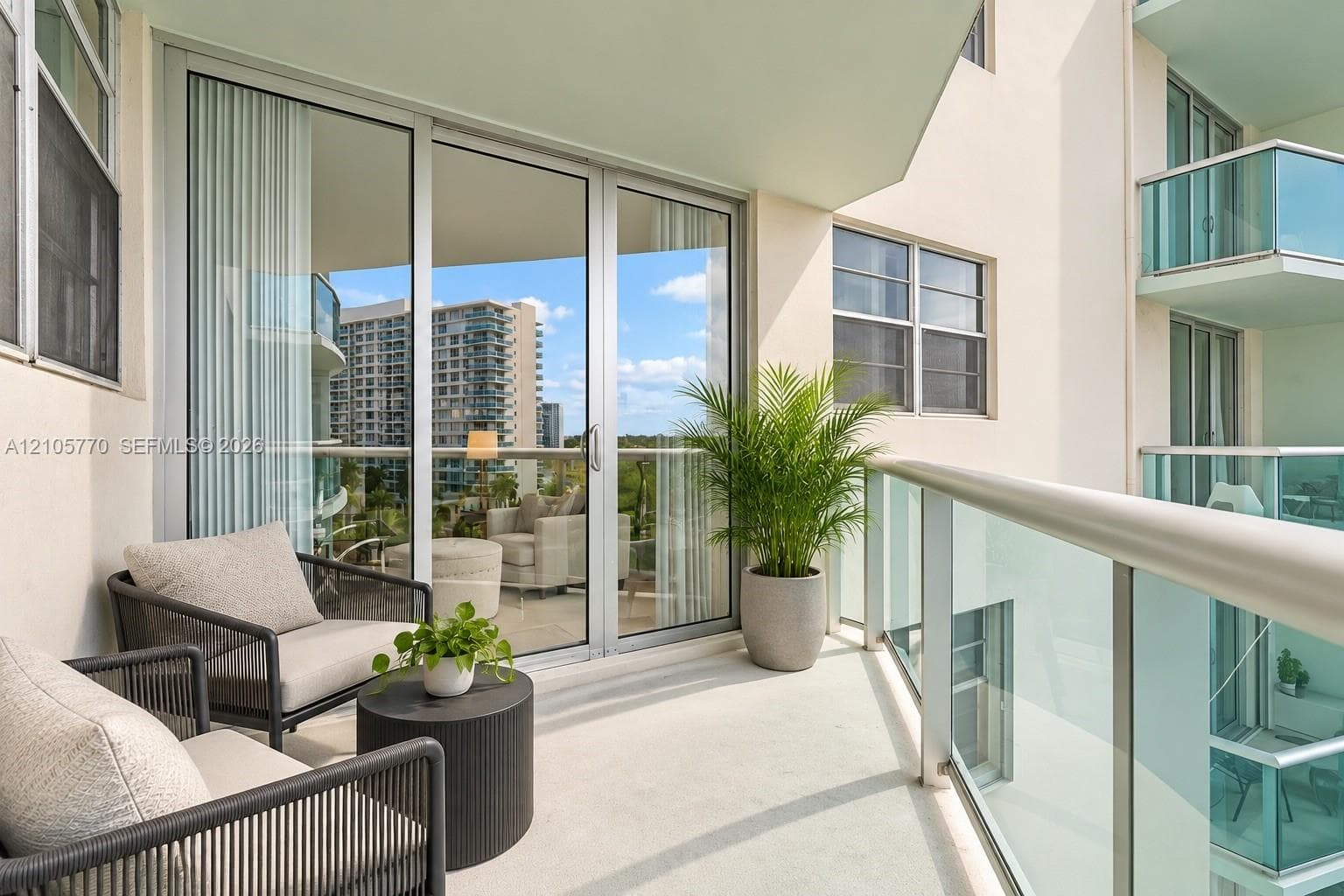 Private balcony featuring glass-panel railings, aluminum-frame sliding glass doors, and concrete flooring
