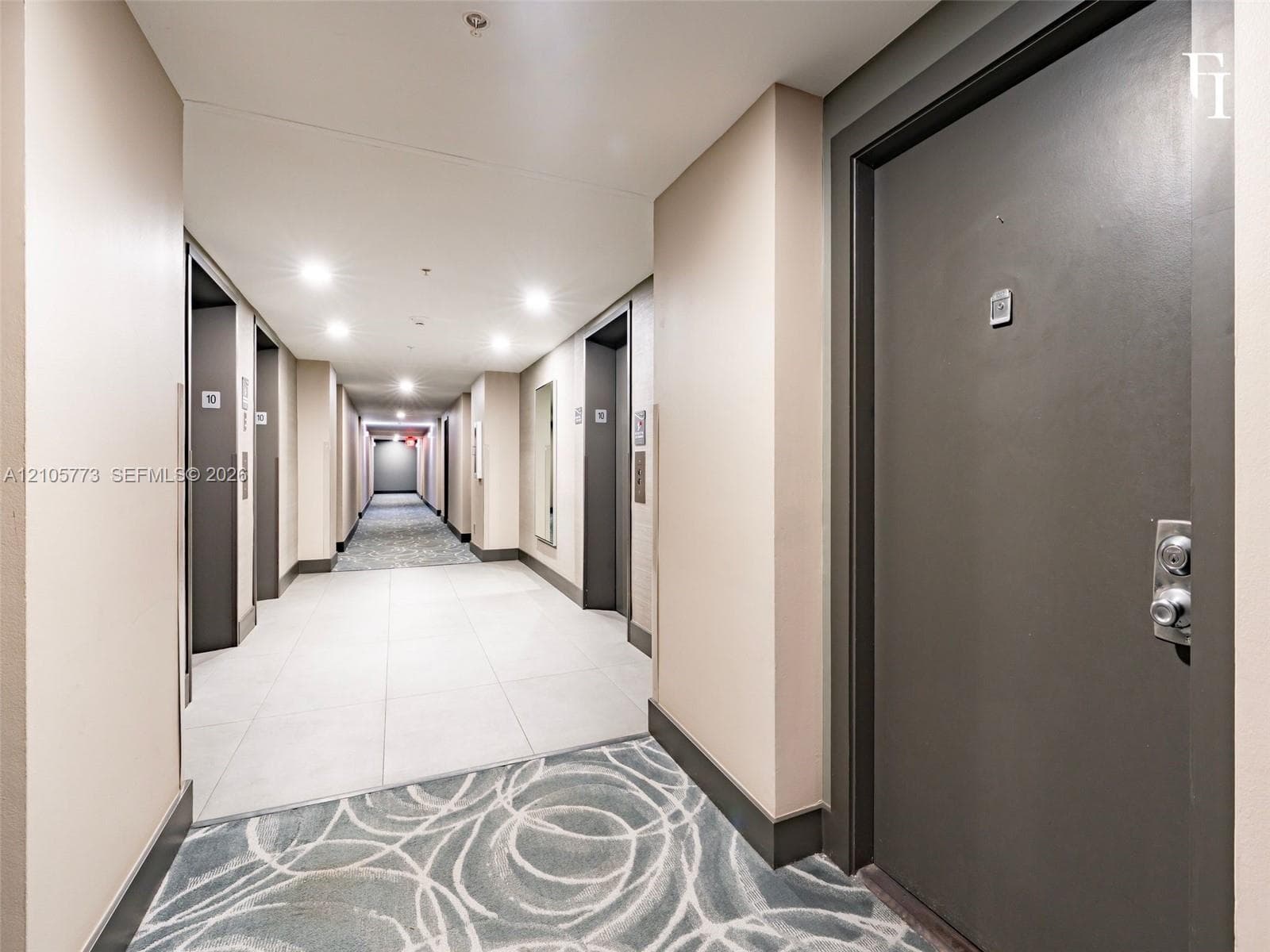 Common hallway featuring neutral wall finishes, large-format tile flooring, recessed ceiling lighting, and patterned wall-to-wall carpeting