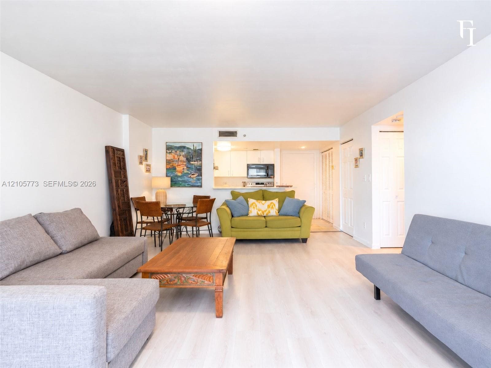 Open-concept living space featuring wood-finish flooring, recessed lighting, and a breakfast bar pass-through to the kitchen with white cabinetry