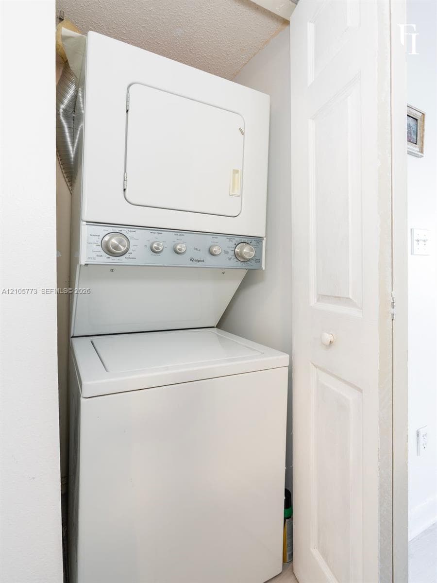 Stacked white washer and dryer unit housed within a dedicated closet featuring a bi-fold door