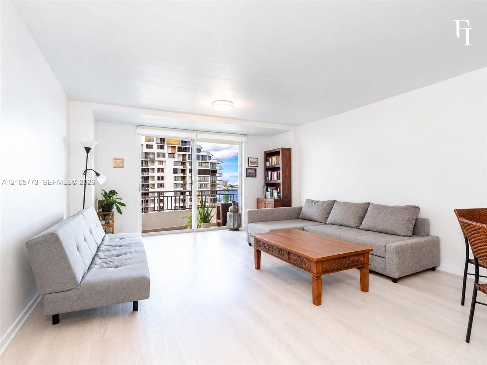 Open-concept living space featuring wood-finish flooring and floor-to-ceiling glass sliding doors providing access to a private balcony