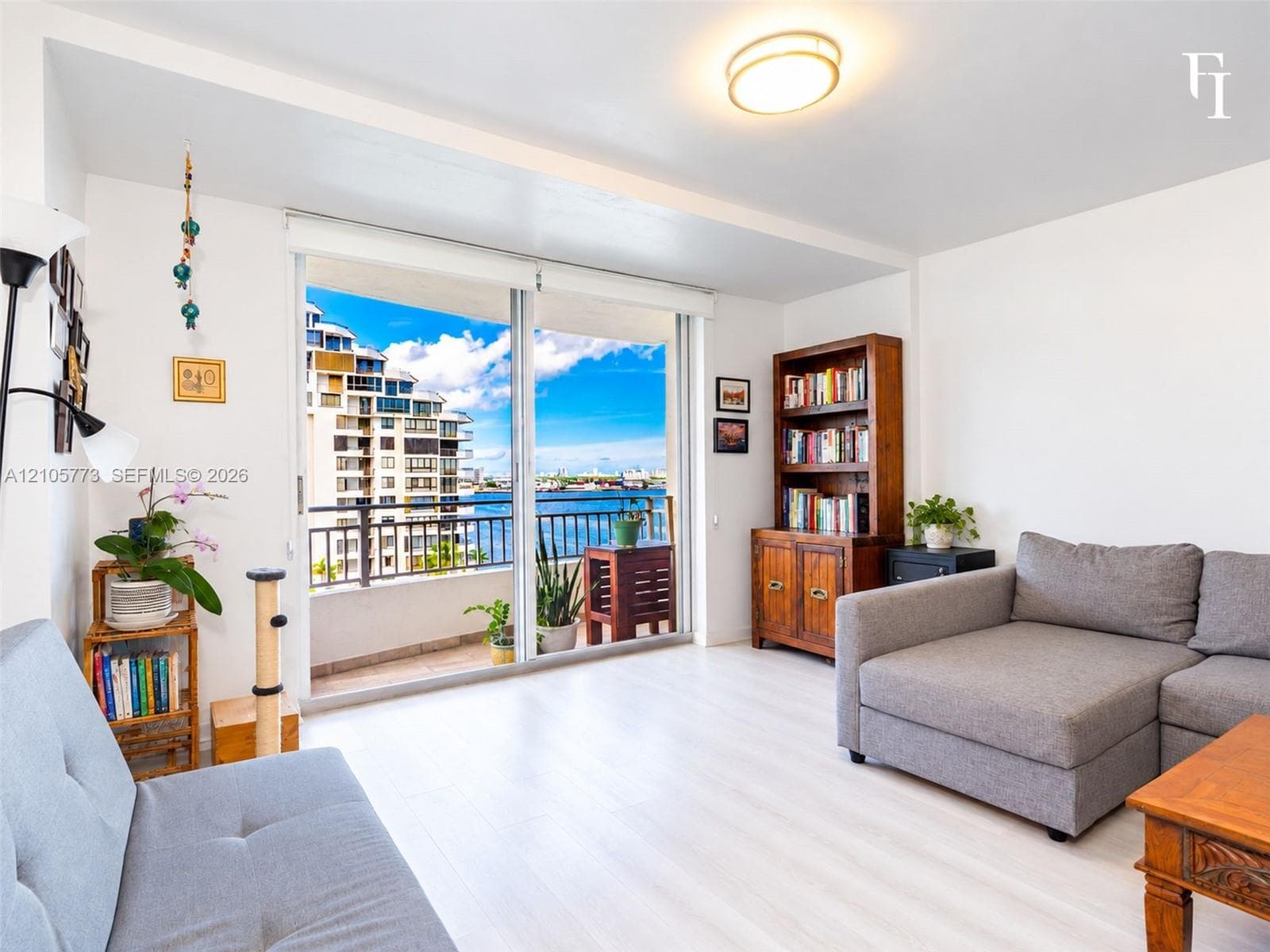 Living space featuring wood-finish flooring, floor-to-ceiling sliding glass doors, and a private balcony overlooking the water