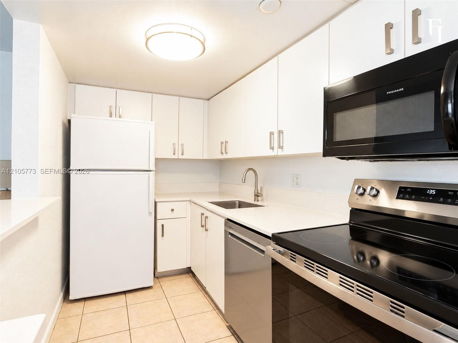 Kitchen featuring white shaker-style cabinetry, solid-surface countertops, stainless steel appliances, a deep basin undermount sink with a gooseneck faucet, and ceramic tile flooring