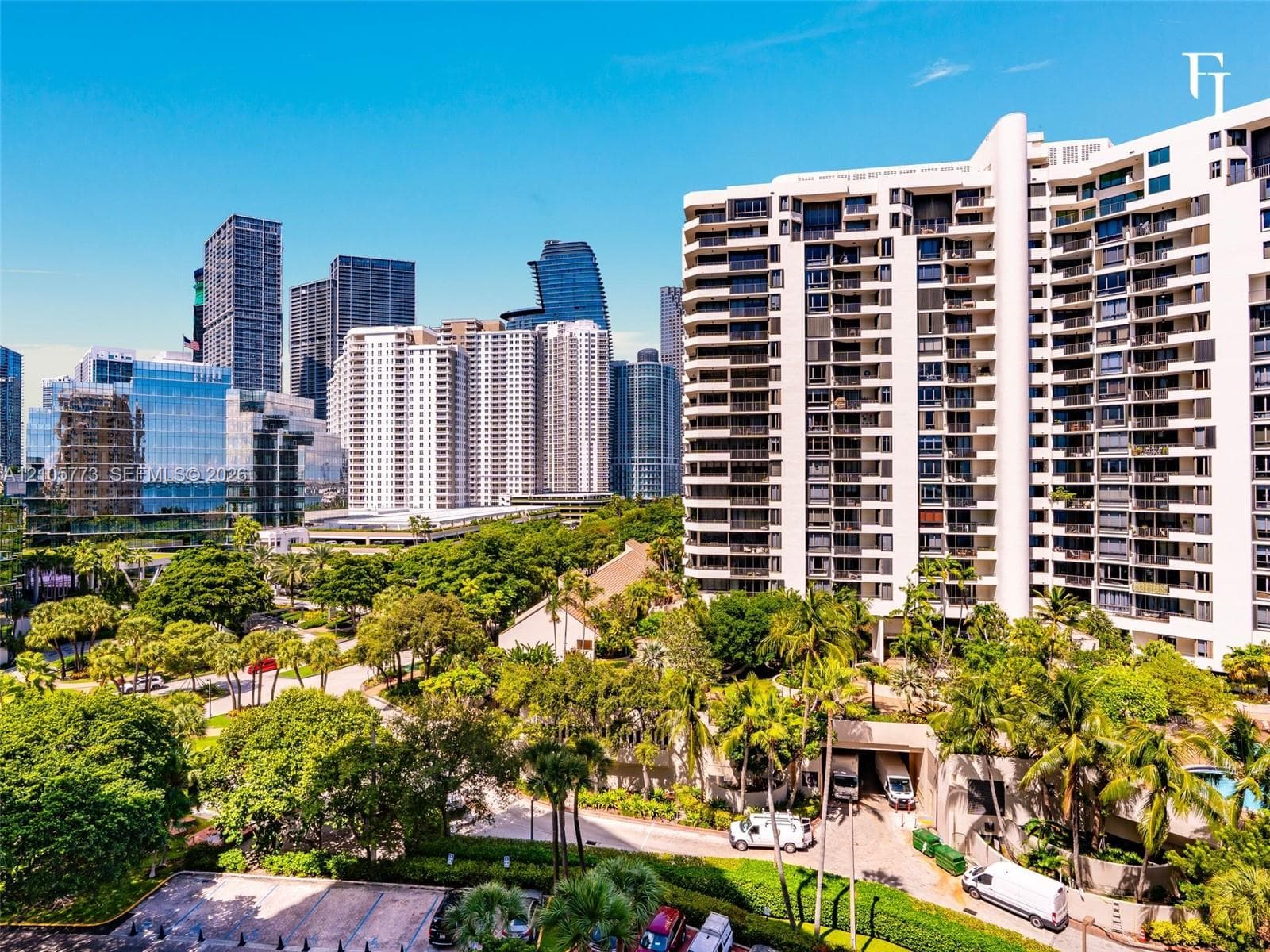 High-rise residential building featuring expansive private balconies, white facade, and surrounding mature landscaping in a metropolitan setting