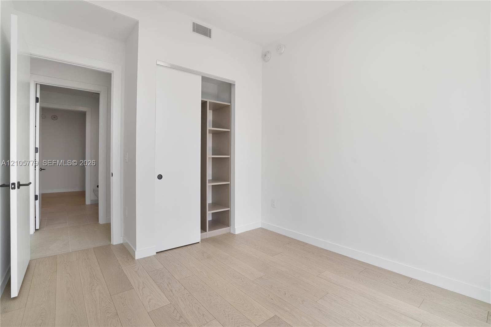 Neutral interior featuring wood-finish flooring, sliding closet doors, and built-in shelving