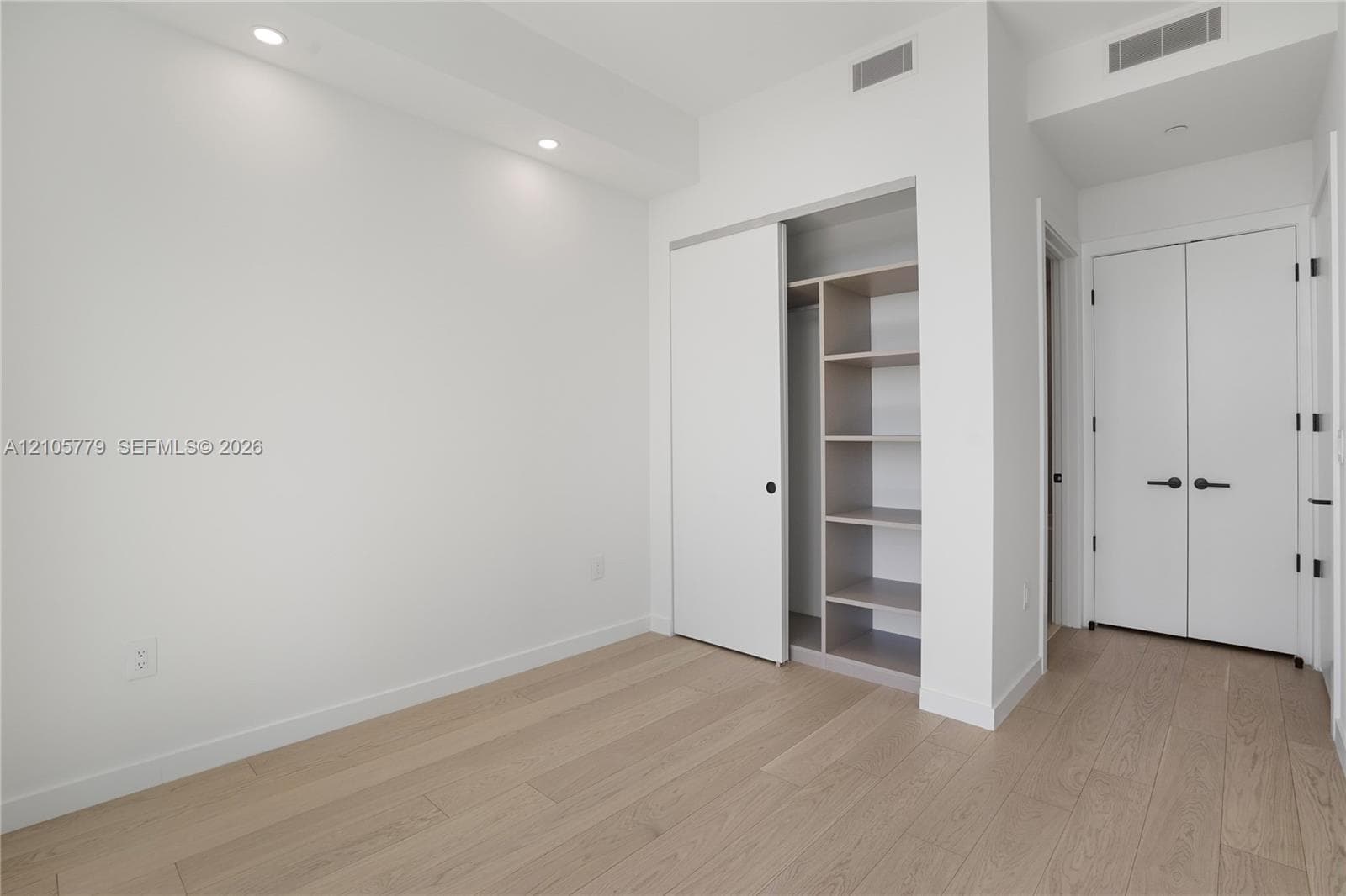 Room featuring wood-finish flooring, recessed lighting, and a closet with built-in shelving
