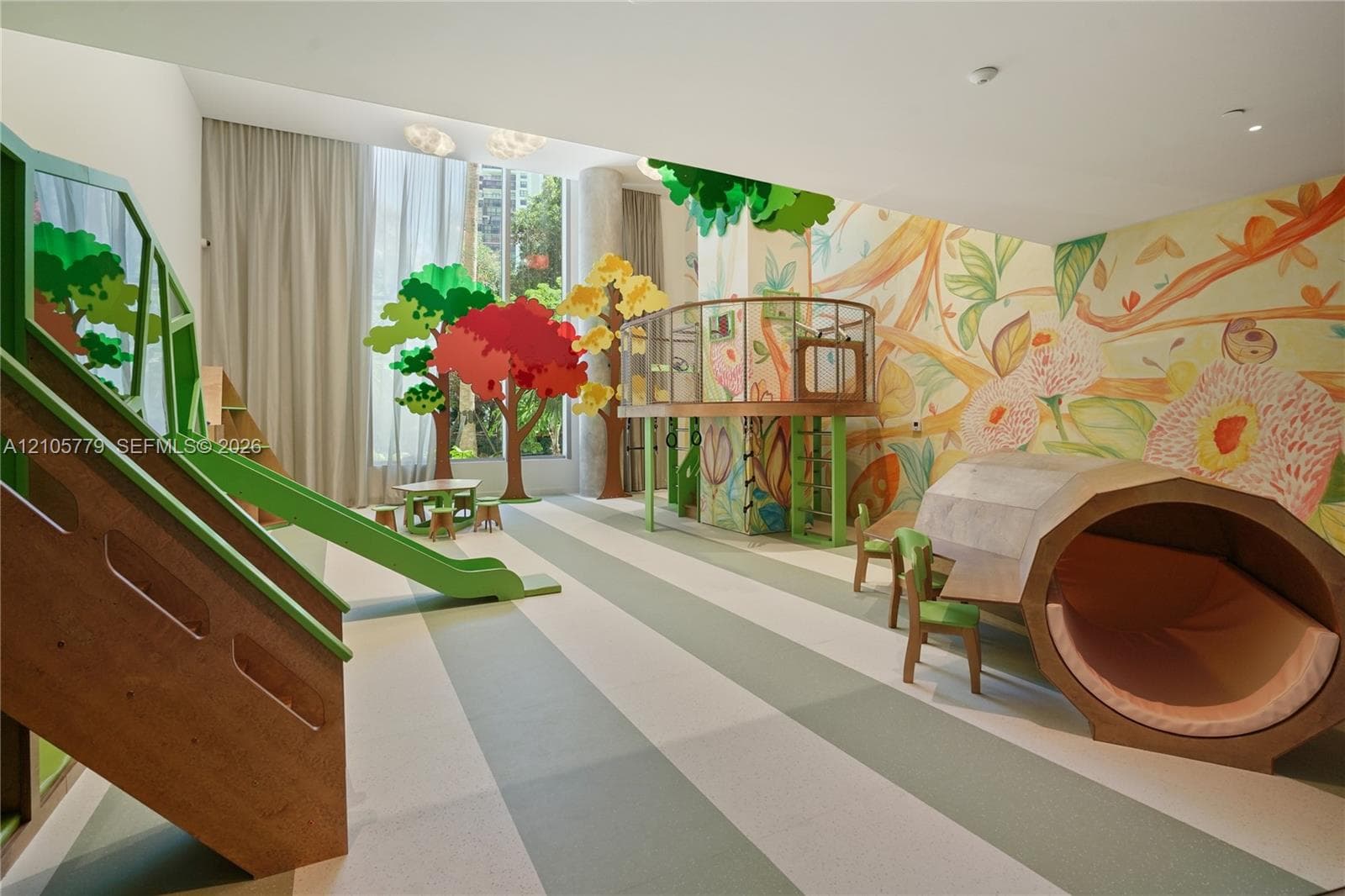 Recreational space featuring custom built-in wood climbing structures, integrated slide, large-scale wall murals, and floor-to-ceiling windows