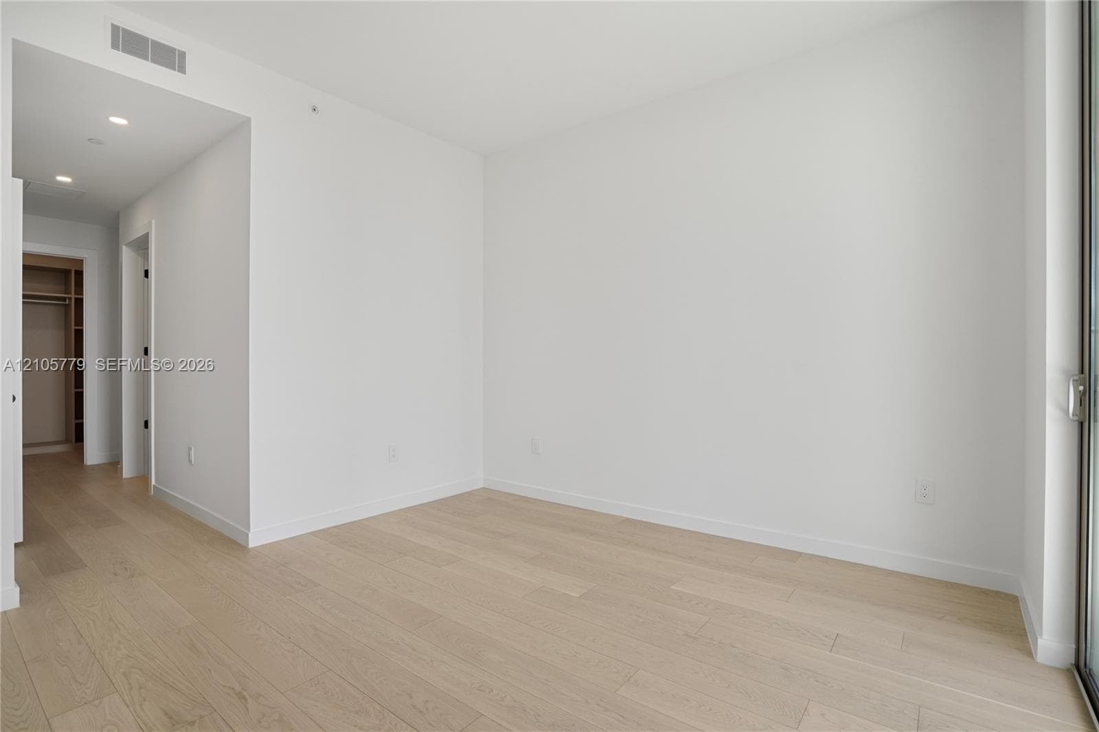 Neutral interior featuring light-tone wood-finish flooring, recessed lighting, and a walk-in closet with built-in shelving