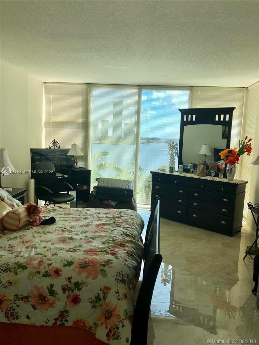 Floor-to-ceiling windows with water and cityscape, polished stone flooring