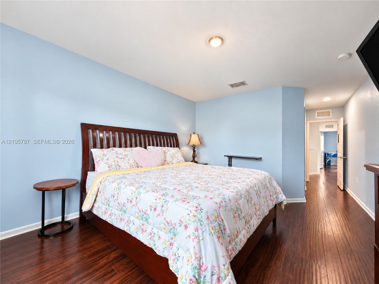Wood-finish flooring throughout, smooth-finish ceilings, and a built-in wall shelf