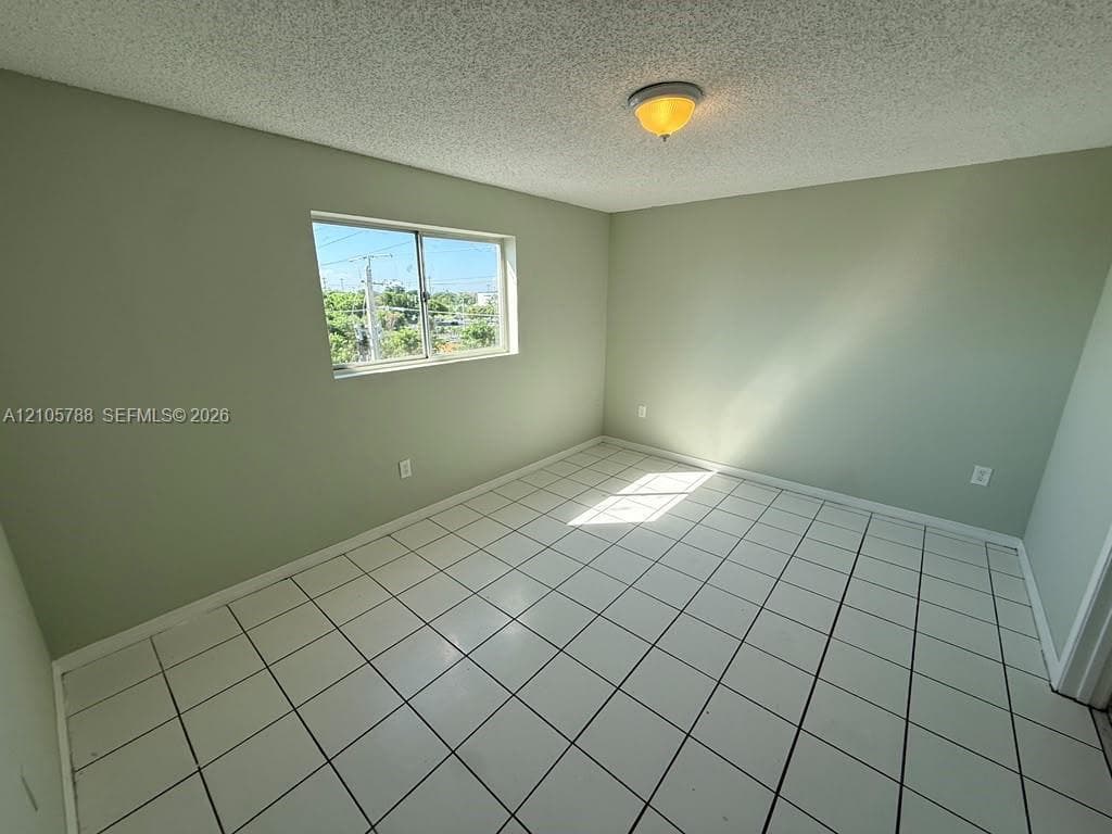 Room featuring neutral-toned walls, white tile flooring, a horizontal sliding window, and a central flush-mount ceiling light fixture