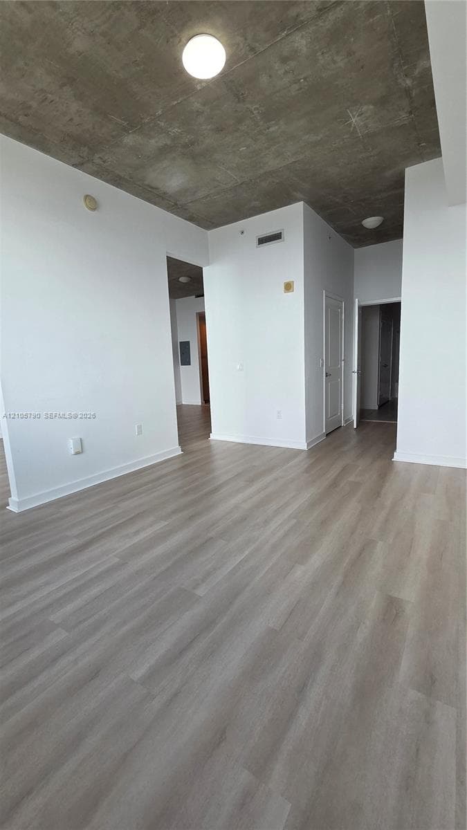 Exposed concrete ceiling, wood-finish flooring, and flush-mount lighting fixtures