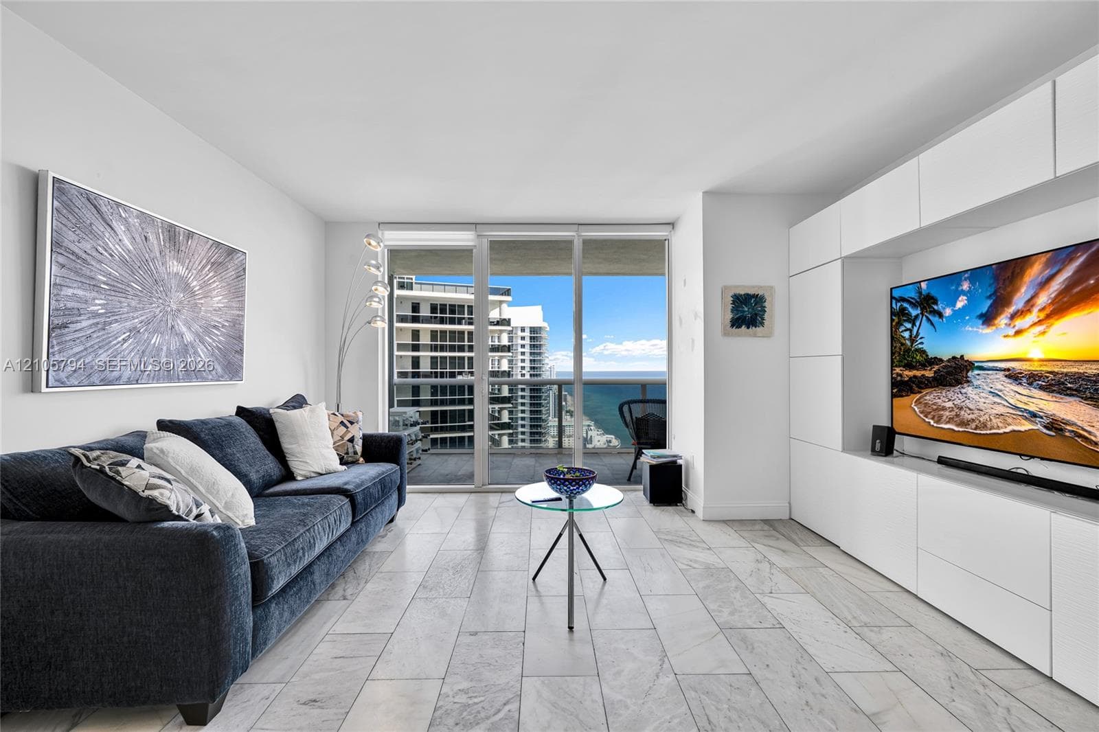 Floor-to-ceiling glass sliding doors, custom white built-in wall cabinetry, stone-finish tile flooring, and a private balcony