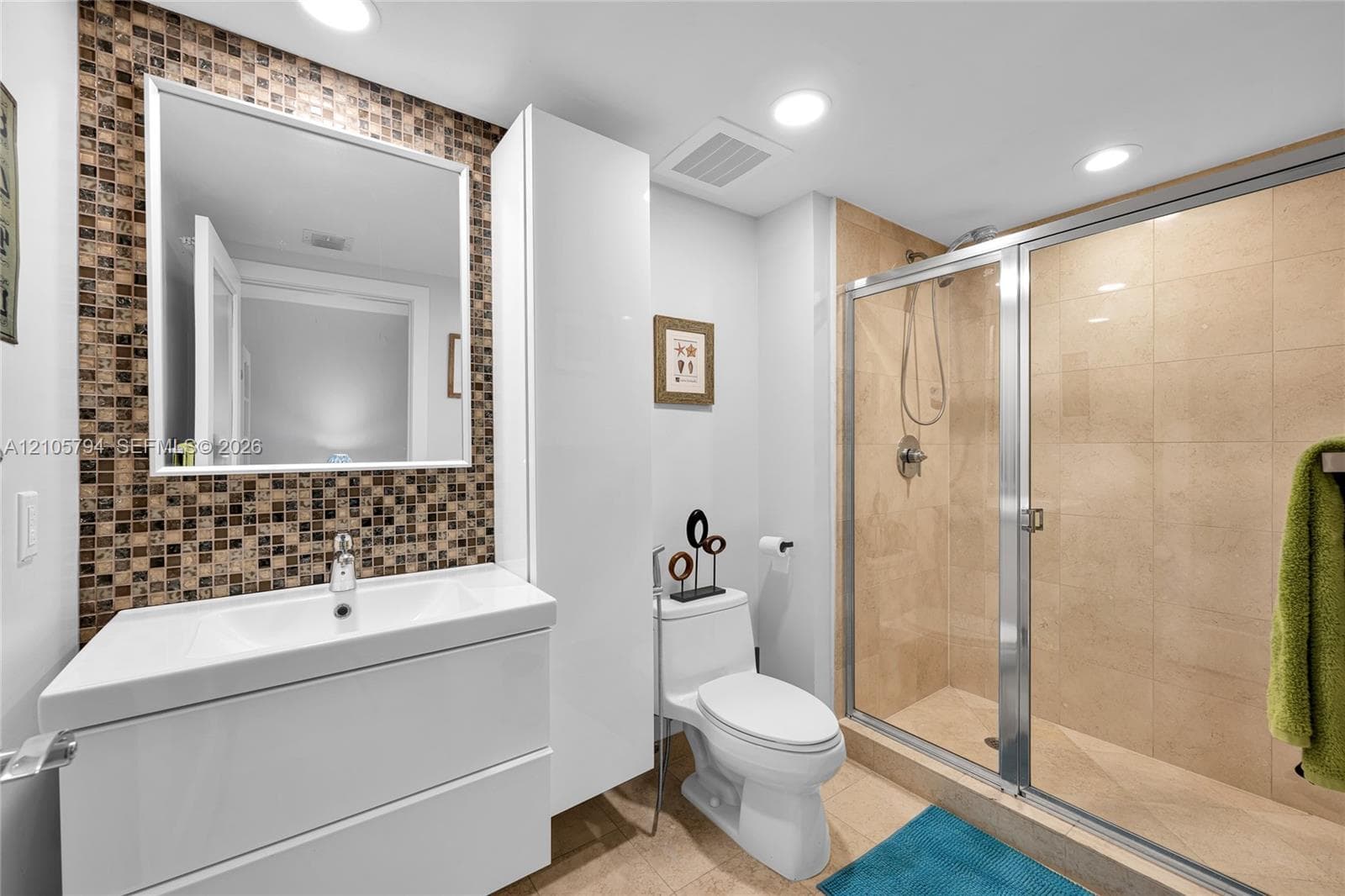 Bathroom featuring a white floating vanity, glass-enclosed shower with tiled walls, mosaic tile backsplash, and built-in vertical cabinetry