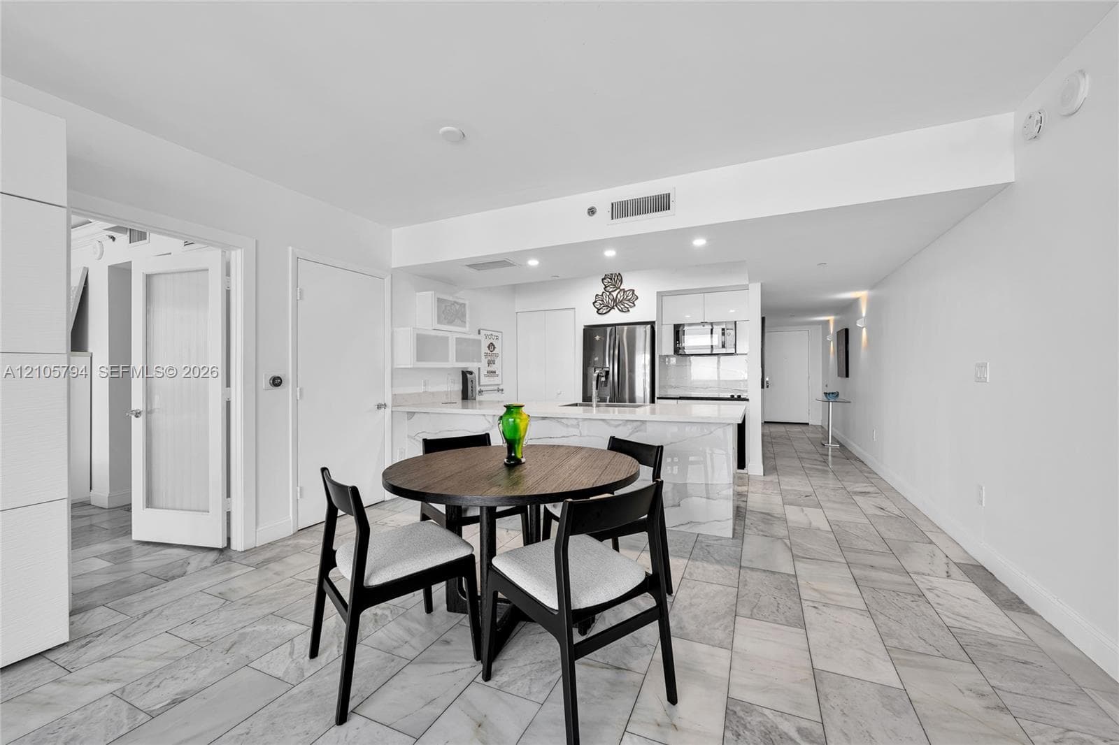 Kitchen featuring a waterfall-edge island, stone-patterned countertops, recessed lighting, and large-format tile flooring