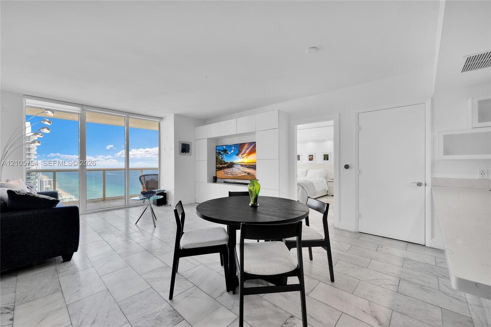 Open-concept interior featuring floor-to-ceiling glass paneling, tile flooring, and custom built-in cabinetry