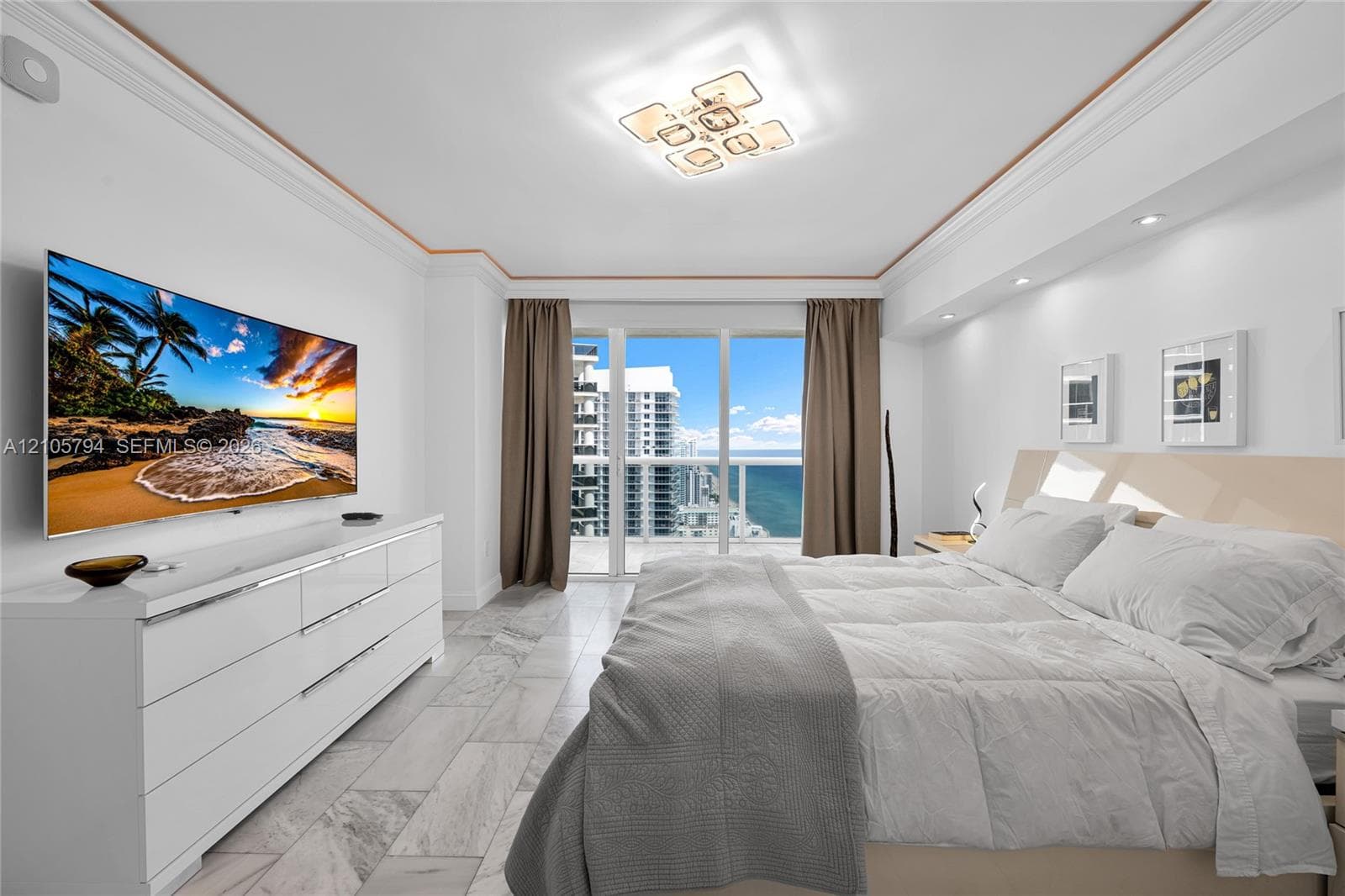 Floor-to-ceiling glass balcony doors, stone-finish tile flooring, recessed ceiling lighting, contemporary geometric flush-mount light fixture, and crown molding