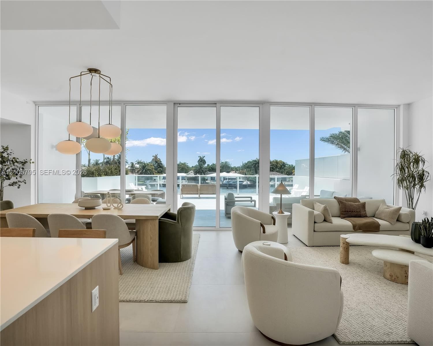 Floor-to-ceiling glass panel walls, polished neutral-toned tile flooring, and a multi-pendant modern light fixture