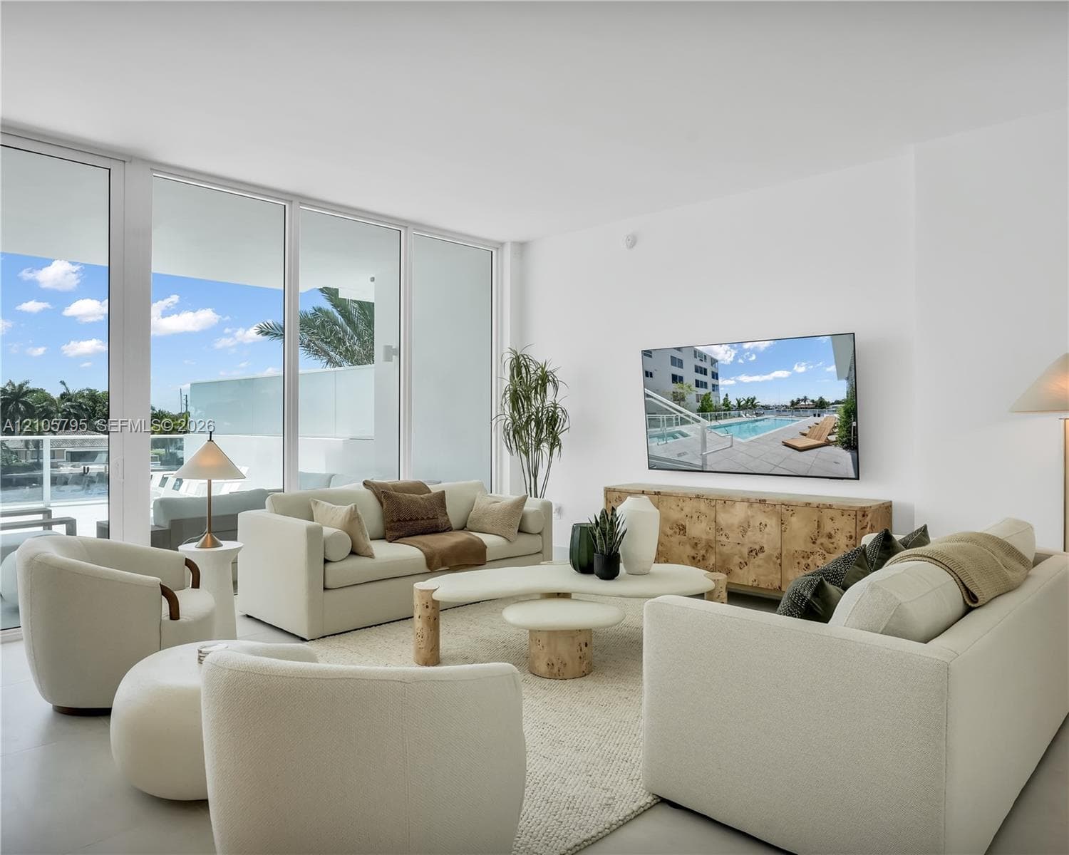 Floor-to-ceiling glass sliding doors, neutral large-format flooring, and direct access to a balcony