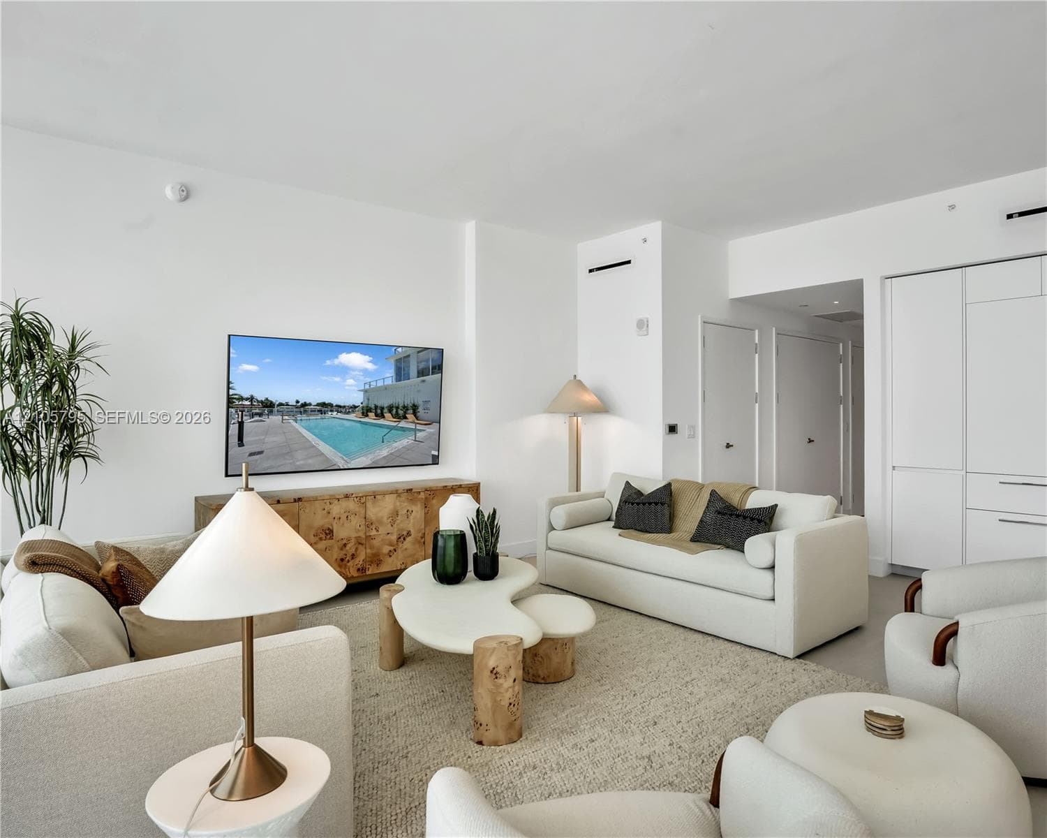 Living area featuring high ceilings, light-toned flooring, recessed lighting, and integrated wall cabinetry