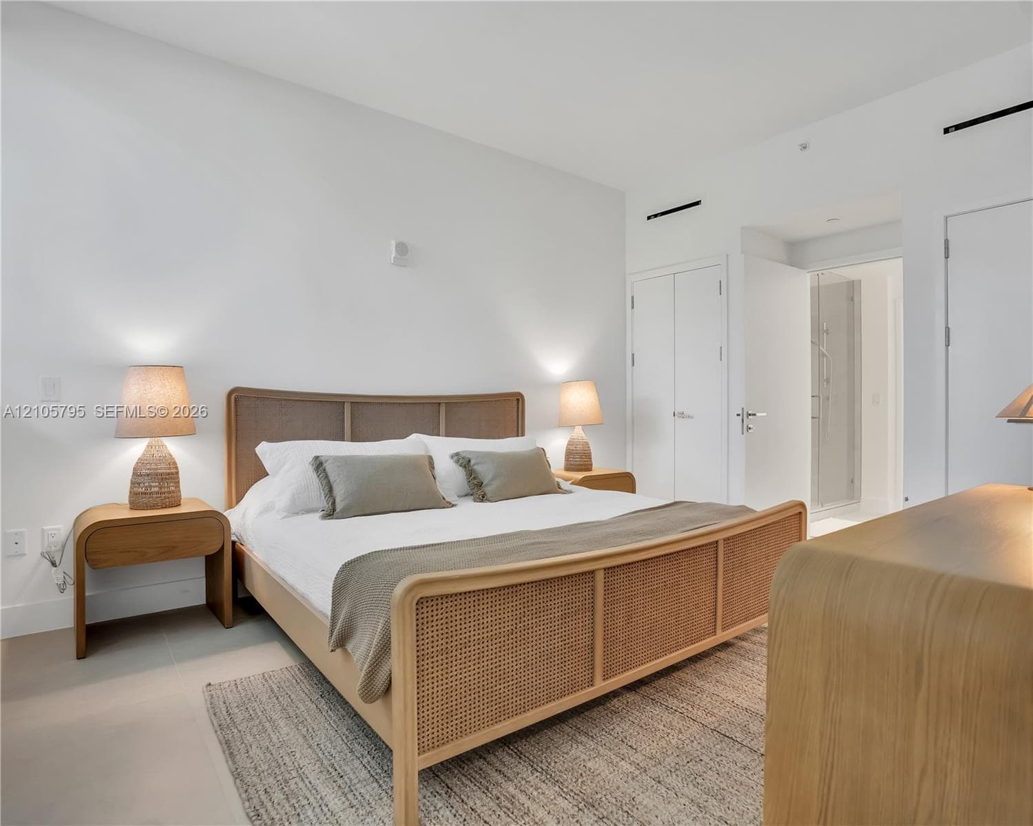 Minimalist room featuring neutral-tone ceramic tile flooring, smooth white walls, and a pair of floor-to-ceiling double-door closets