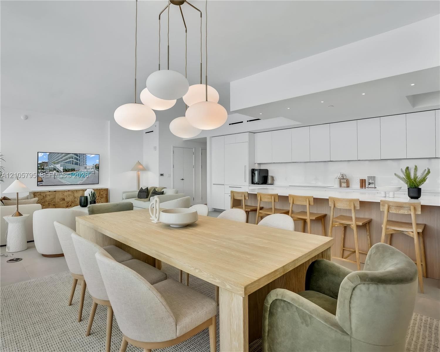 Modern kitchen featuring floor-to-ceiling flat-panel cabinetry, a solid-surface waterfall edge island, and recessed lighting