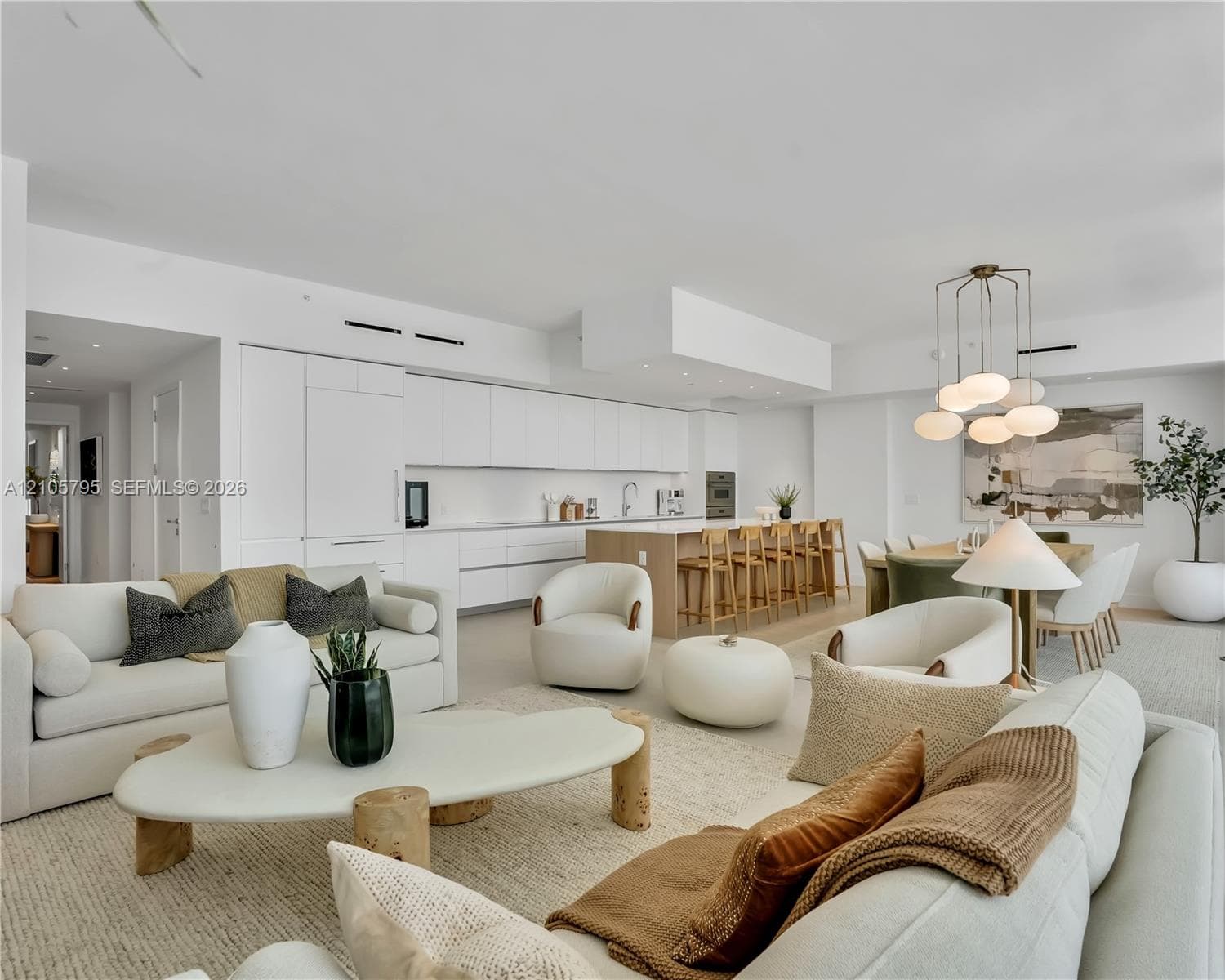 Open-concept kitchen featuring integrated white cabinetry, a center island with wood-finish paneling, built-in appliances, recessed lighting, and a multi-pendant light fixture