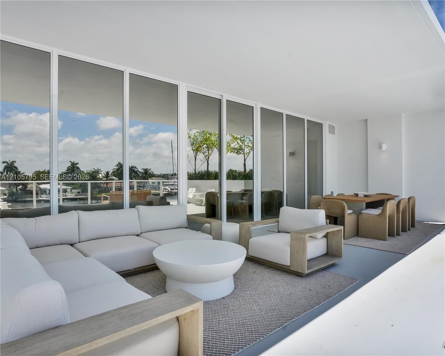 Covered terrace featuring floor-to-ceiling glass wall panels, minimalist structural columns, and a smooth, level ceiling finish