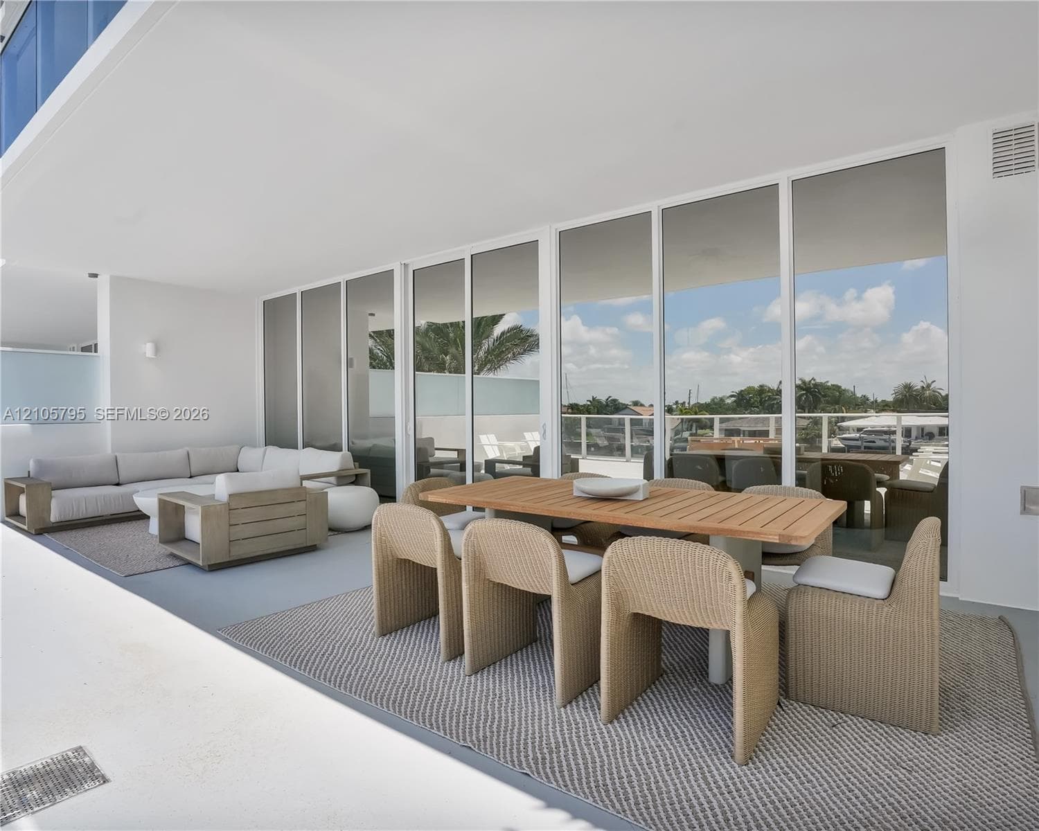 Expansive covered terrace featuring floor-to-ceiling glass wall panels, smooth concrete flooring, and an attached white railing system