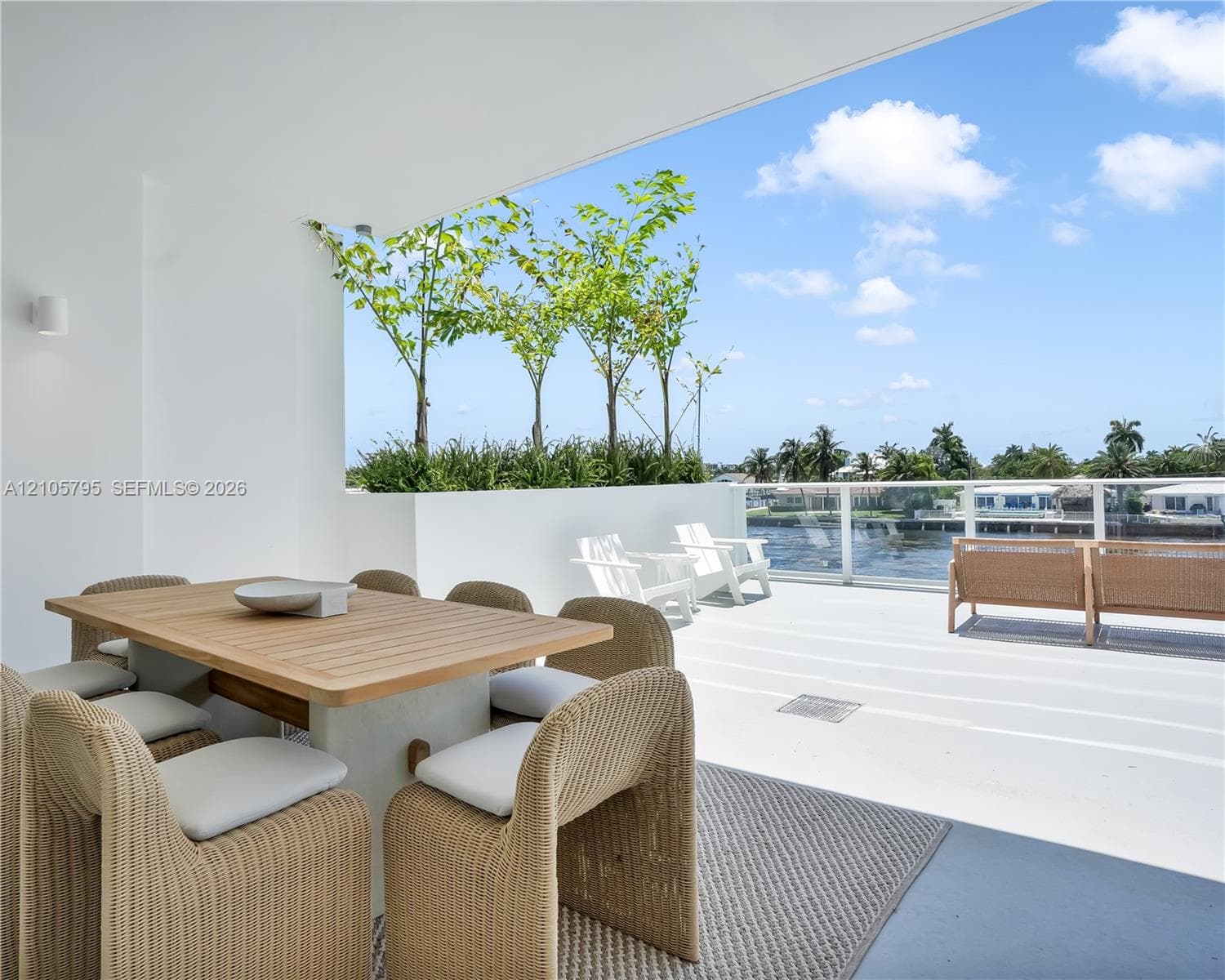 Covered terrace featuring a glass panel railing, built-in planter boxes with mature trees, and smooth concrete flooring