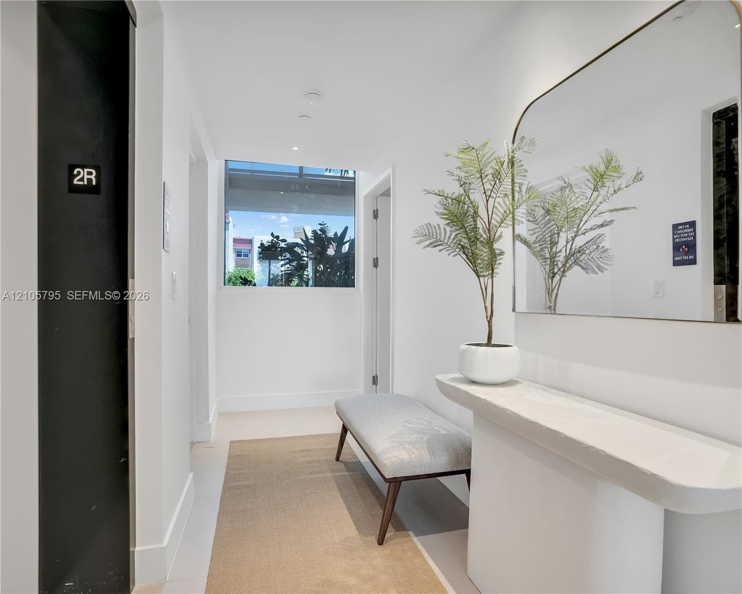 Entryway featuring a matte black elevator door, a built-in stone-finish console table, and a large wall-mounted mirror